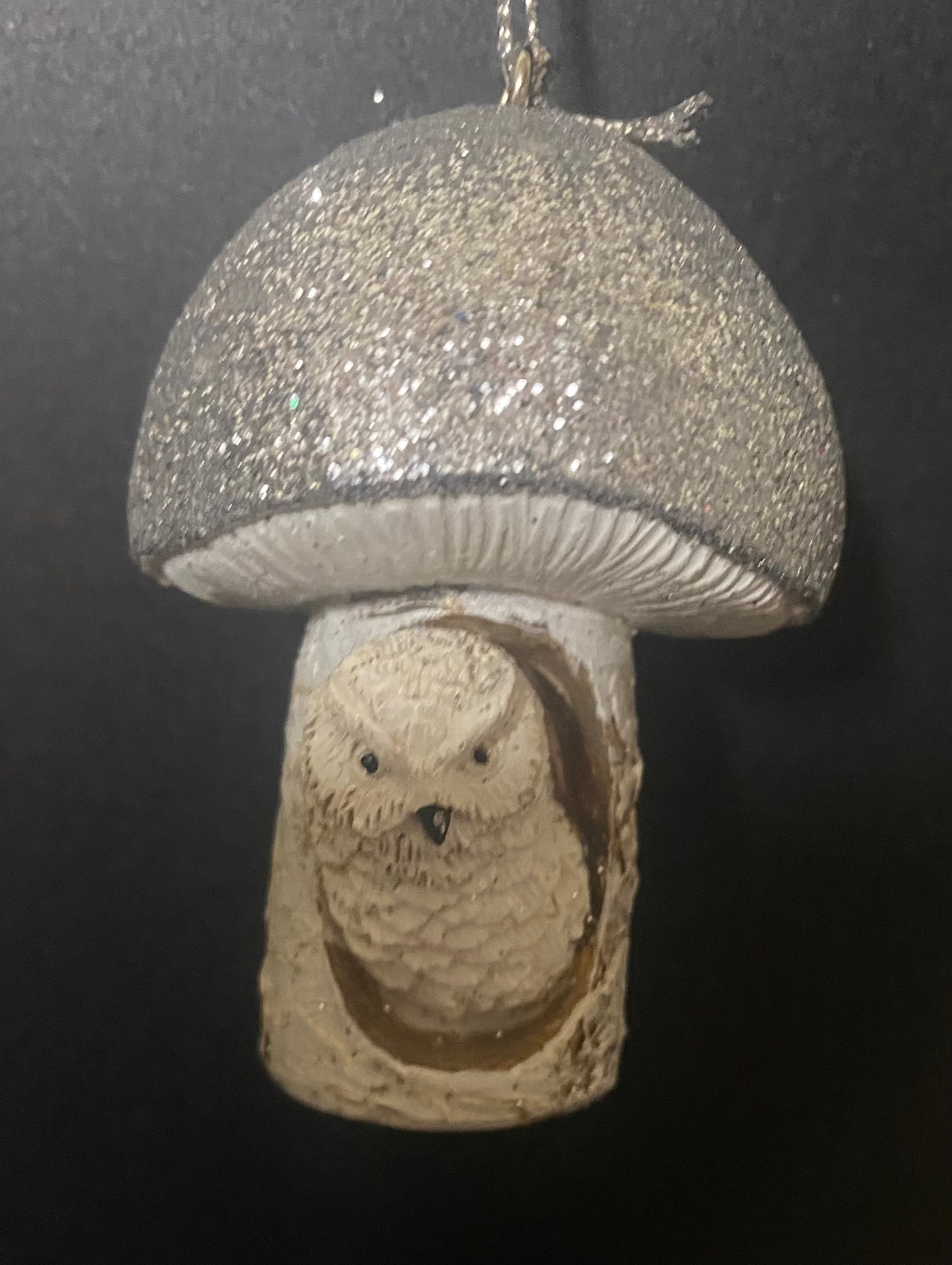 Decorative ornament with a silver glittery cap and owl design on a dark background
