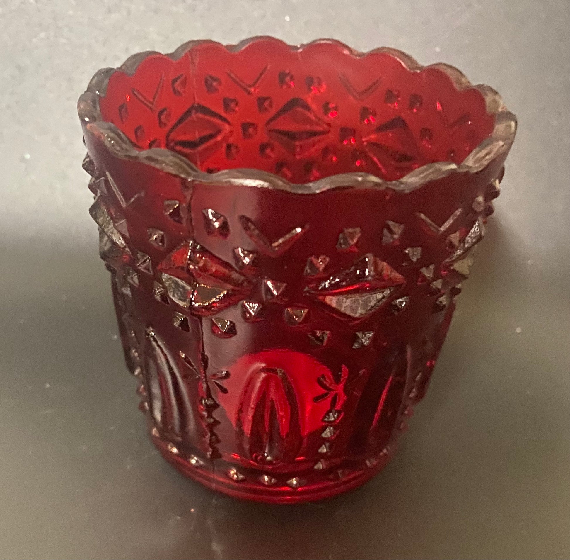 Red glass candle holder with intricate patterns on a gray background