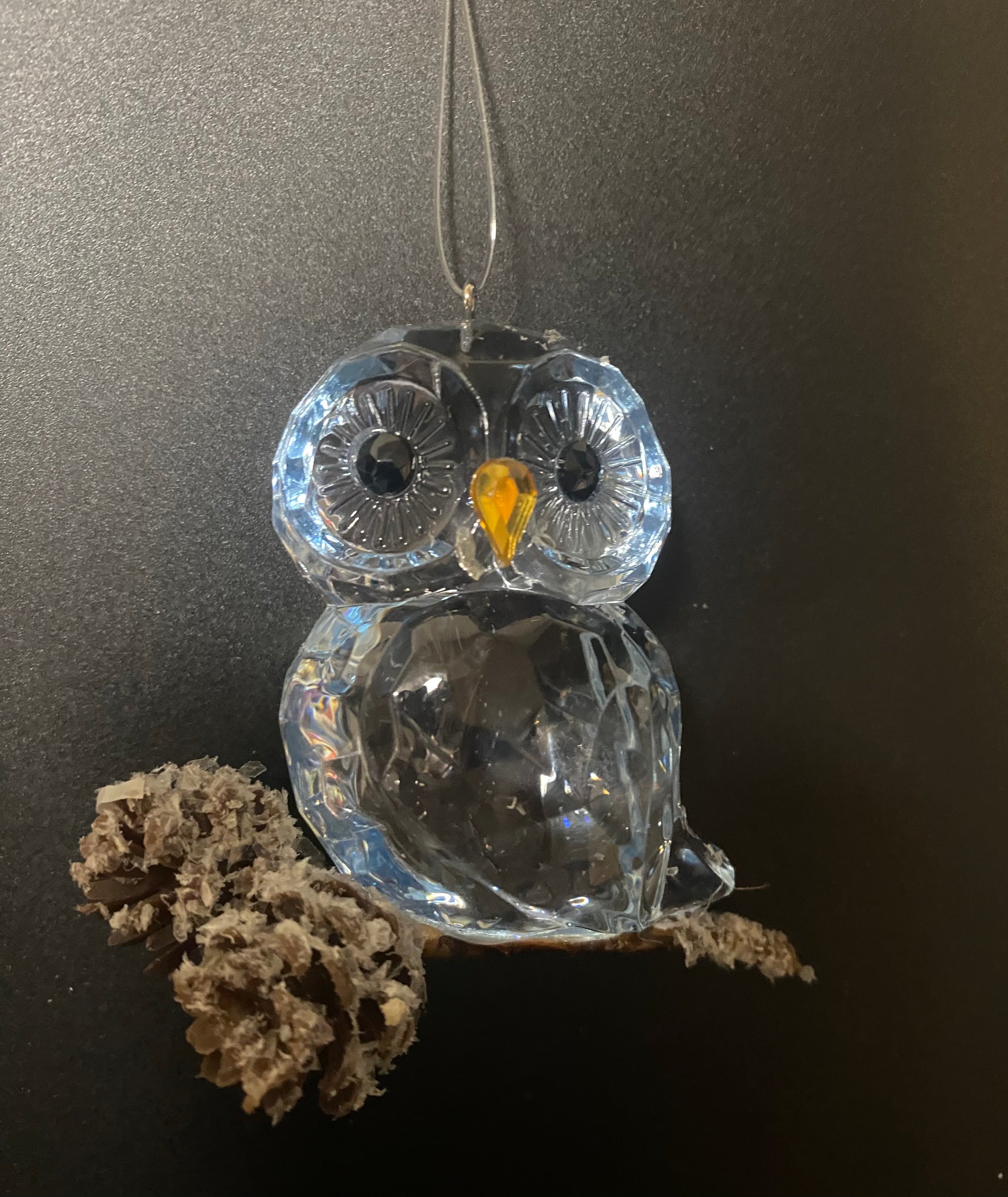 Clear glass owl ornament with a yellow center on a dark background