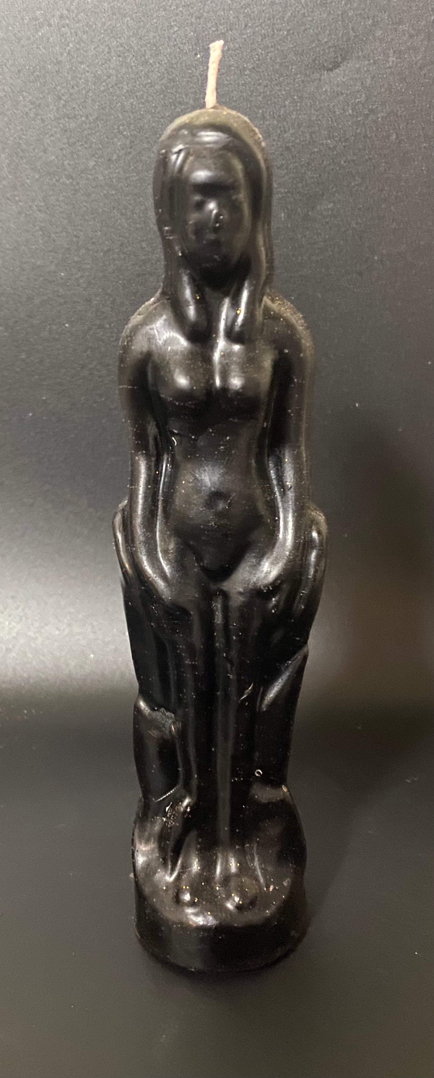 Black candle shaped like a standing figure on a dark background