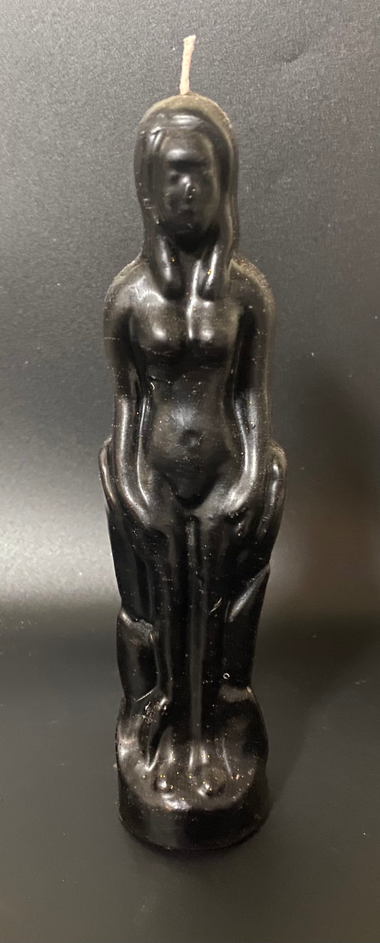 Black candle shaped like a standing figure on a dark background