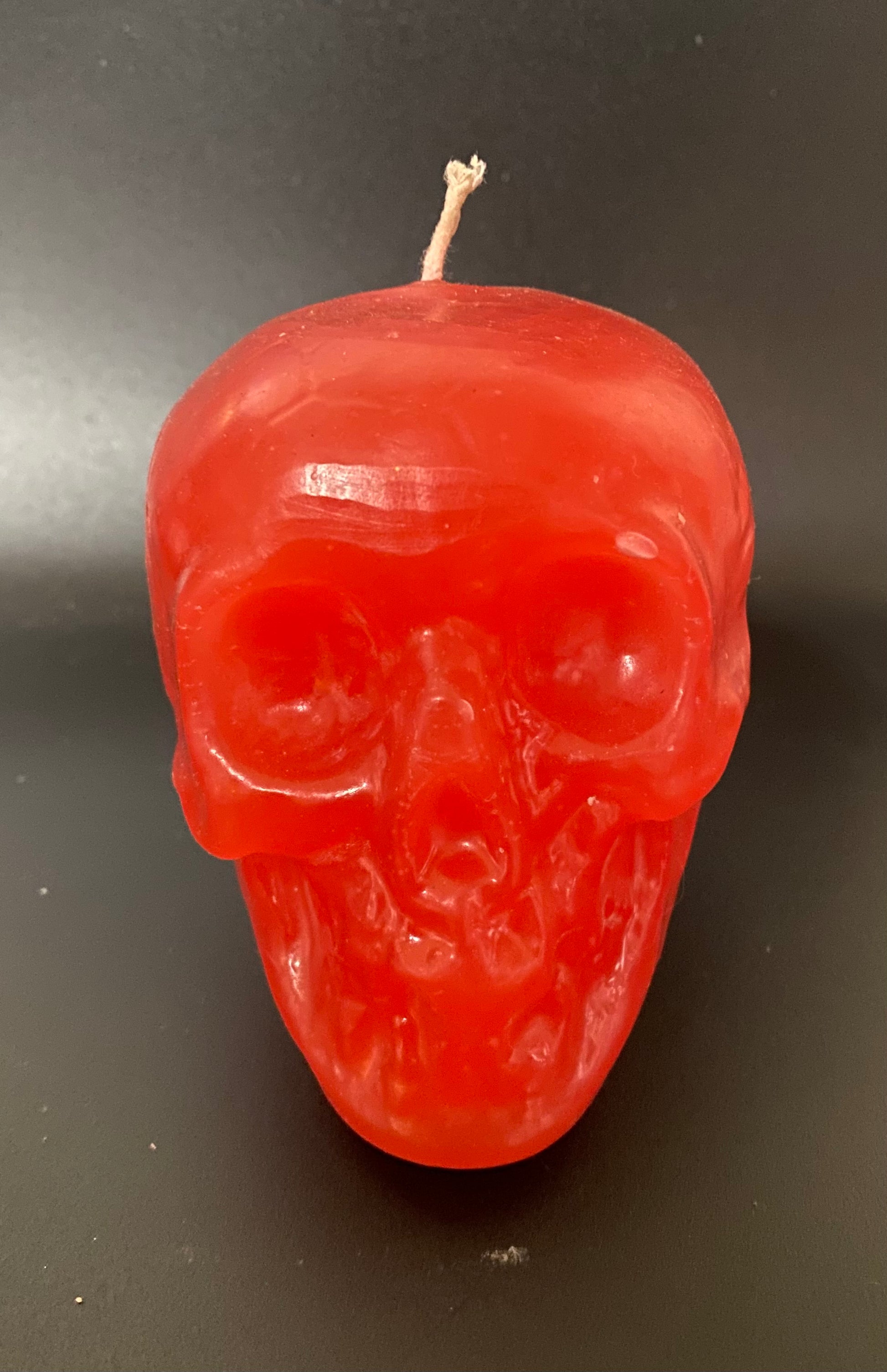 Red skull-shaped candle on a black background