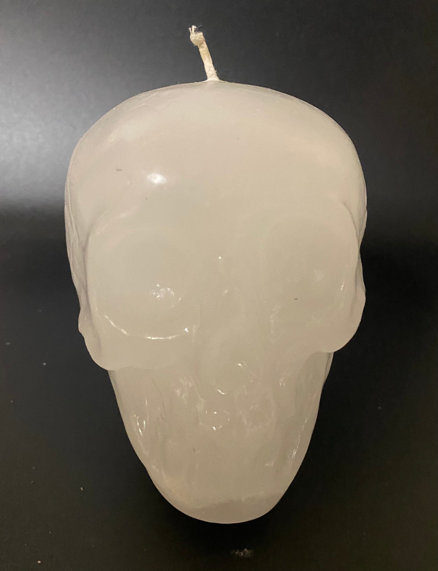 White skull-shaped candle on a black background