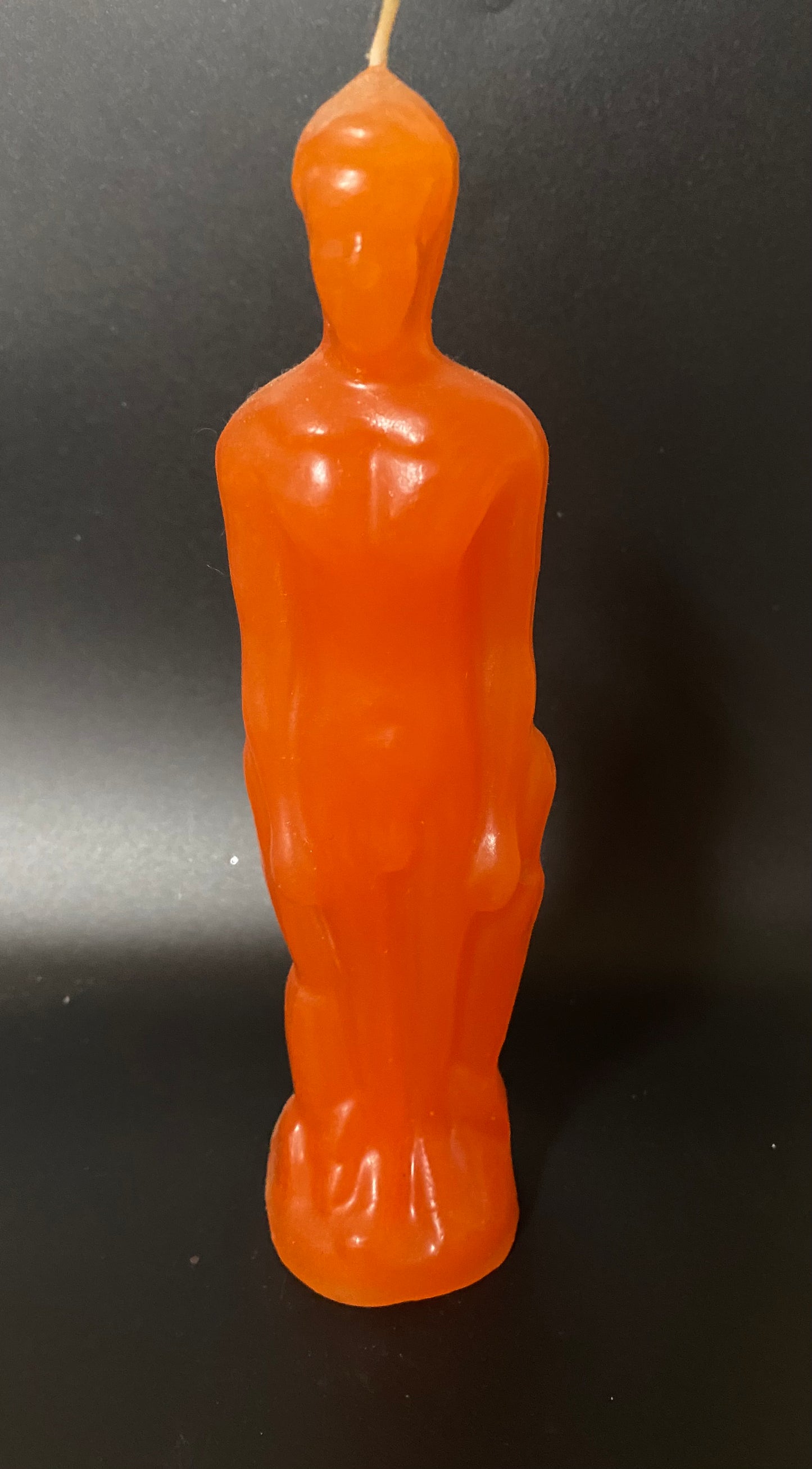 Orange candle shaped like an Oscar statue on a black background