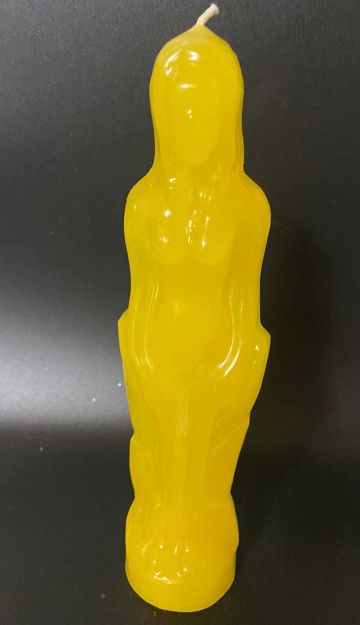 Yellow candle shaped like a person on a black background
