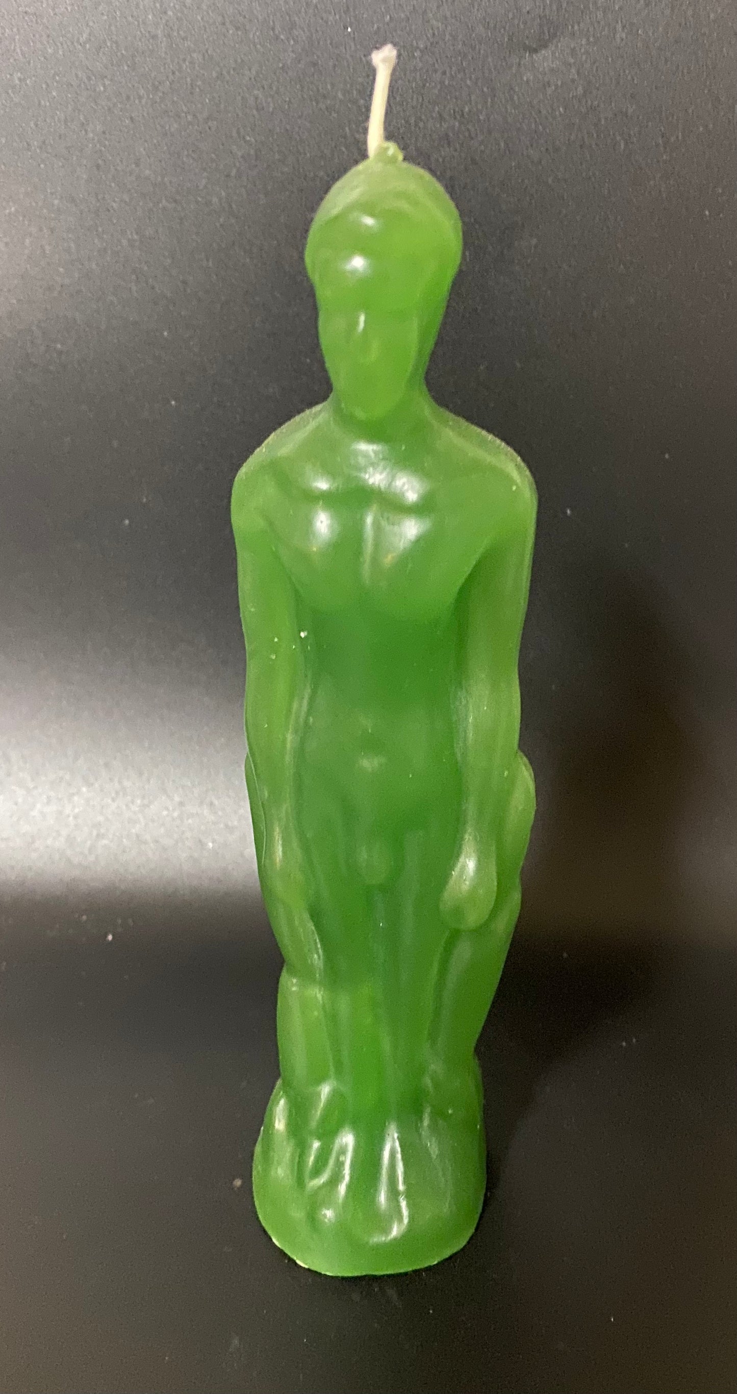 Green candle shaped like a person on a black background
