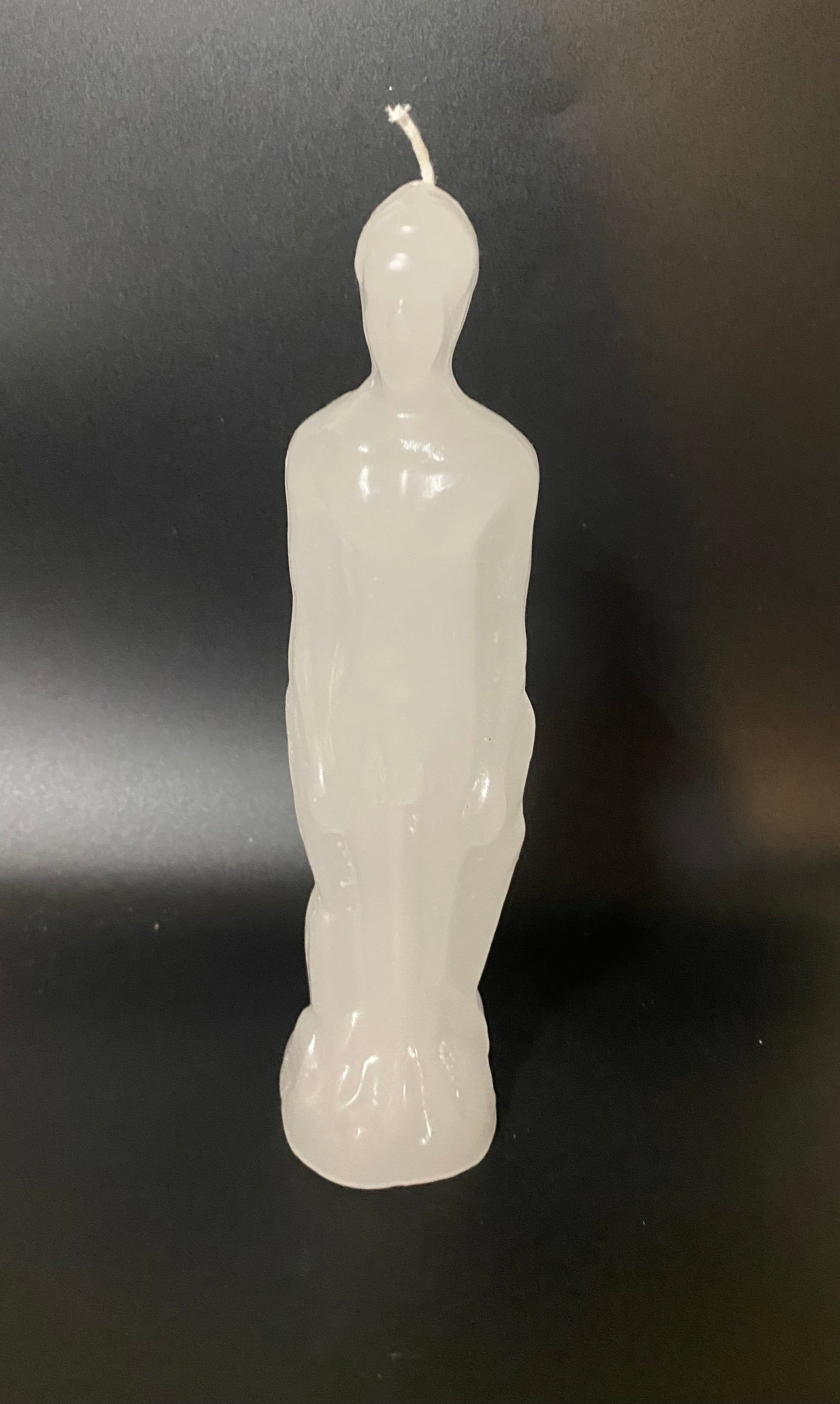 White candle shaped like a person on a black background