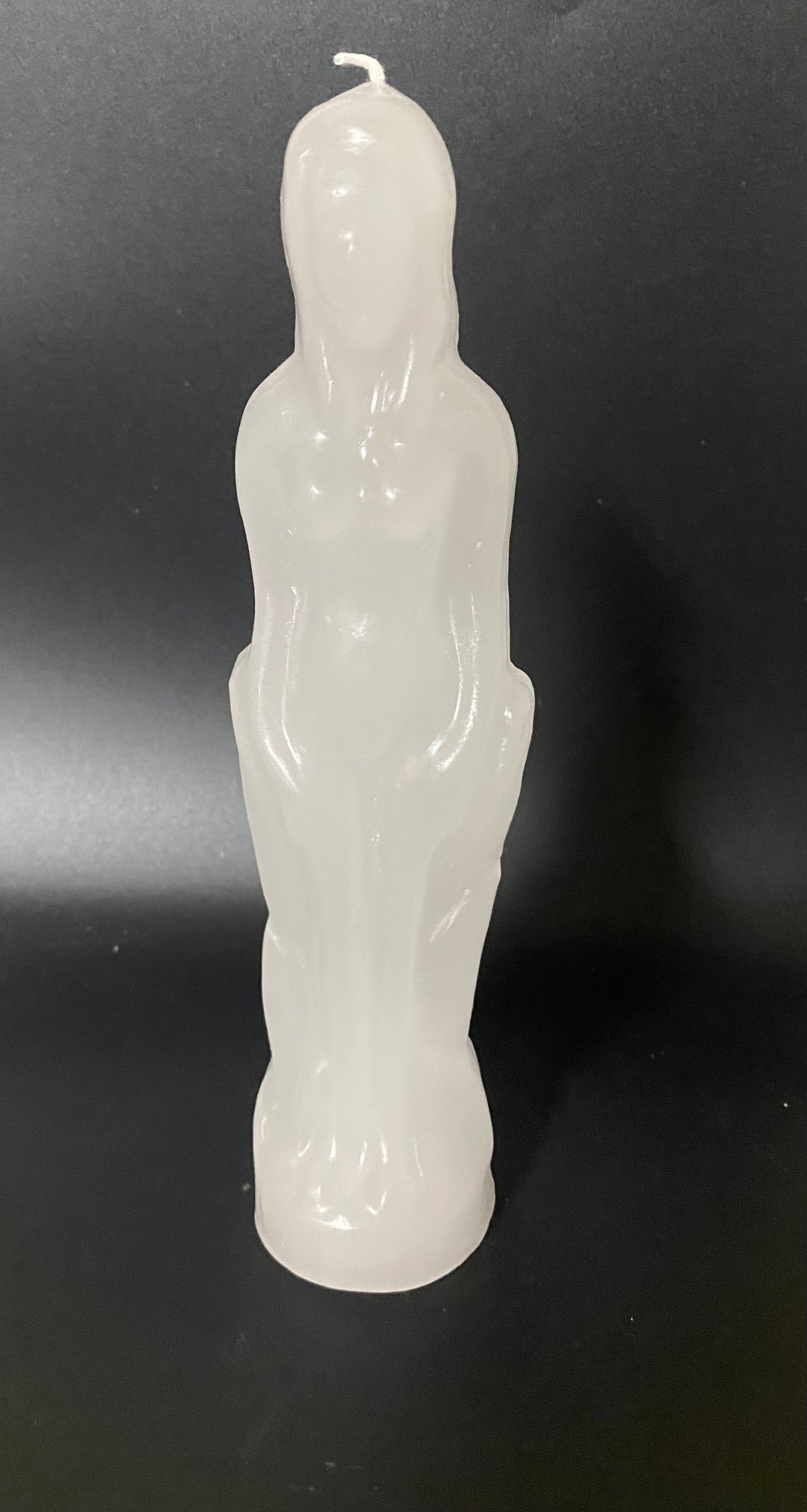 White candle shaped like a person on a black background