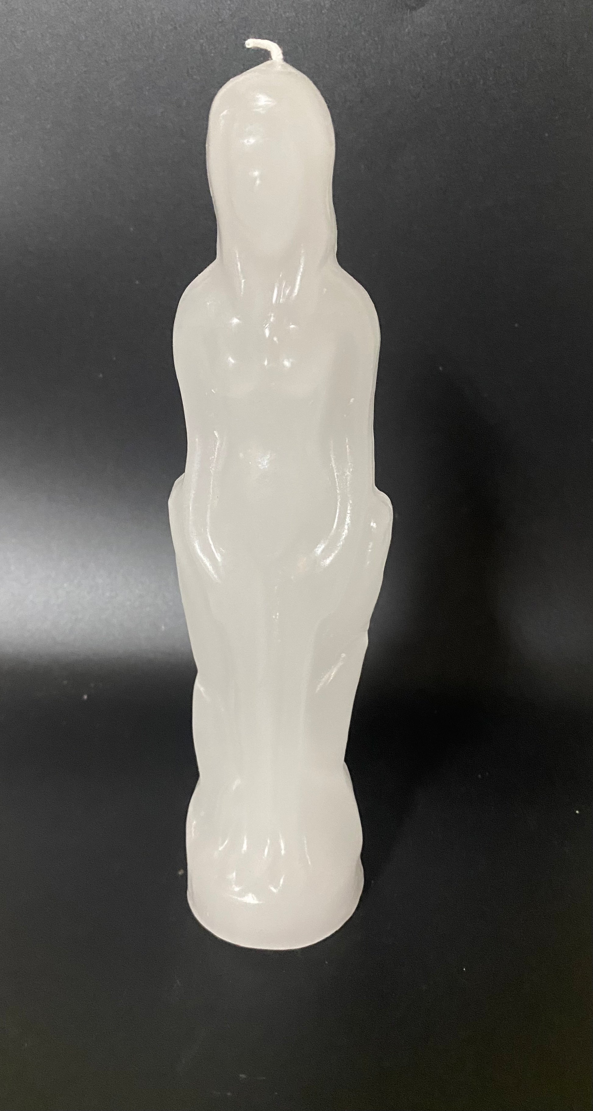 White candle shaped like a person on a black background