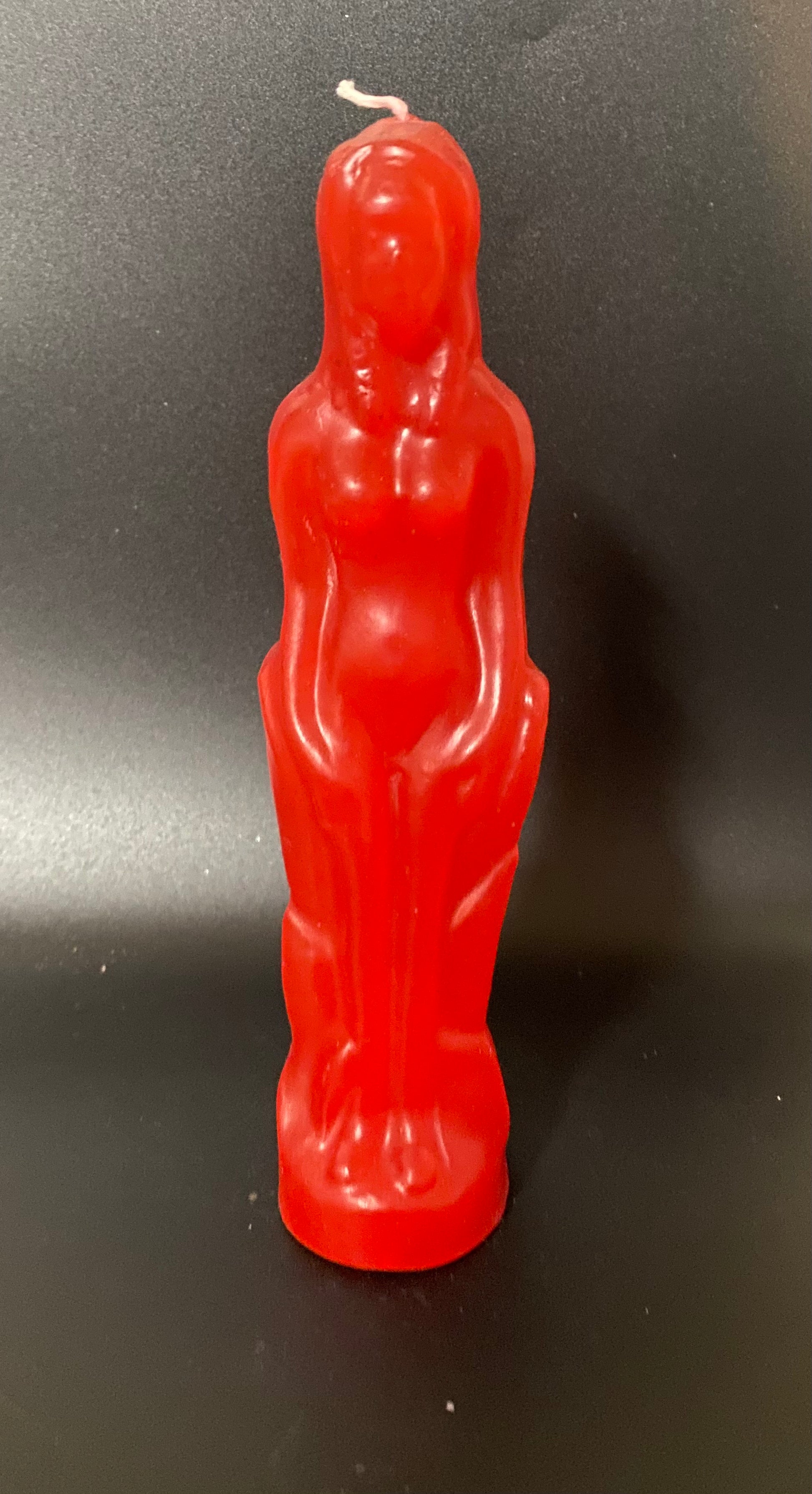 Red candle shaped like a person on a black background