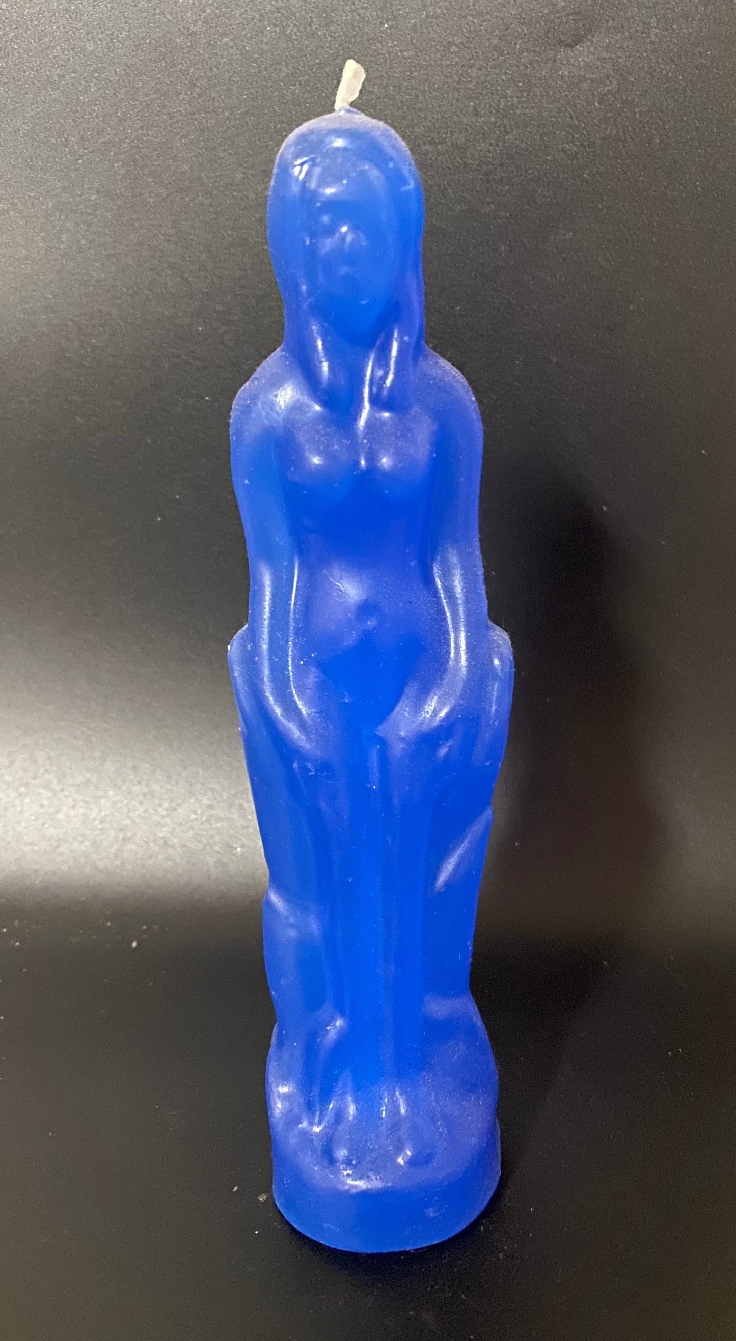Blue statue-shaped candle on a black background