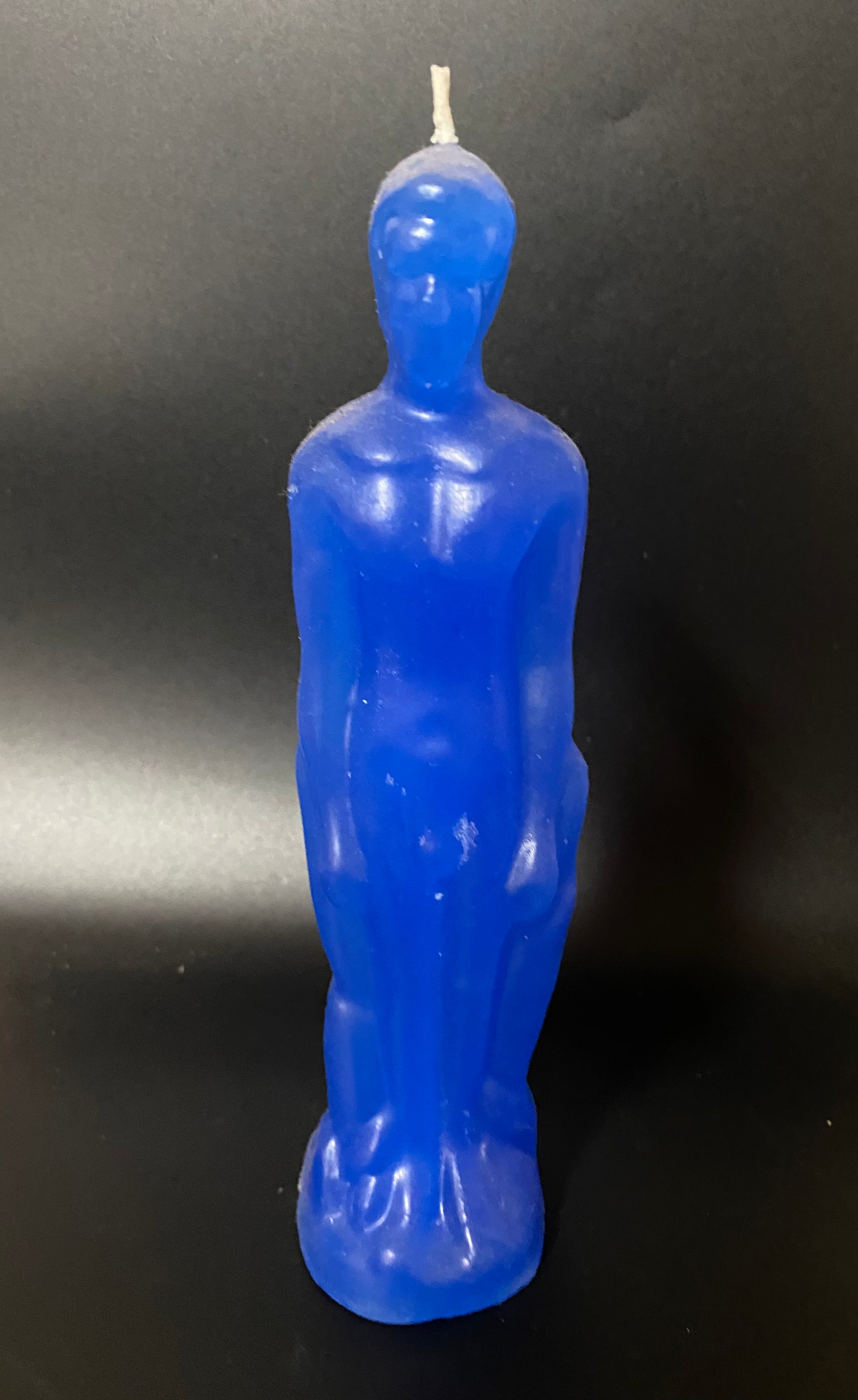 Blue candle shaped like an Oscar statue on a black background