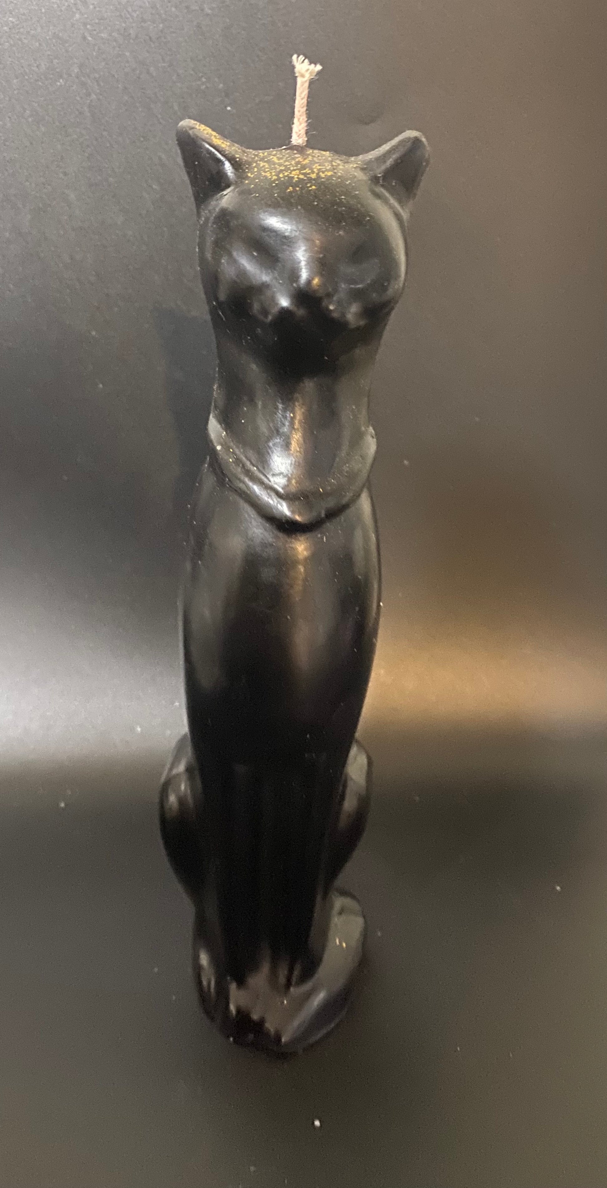 Black cat-shaped candle on a dark background