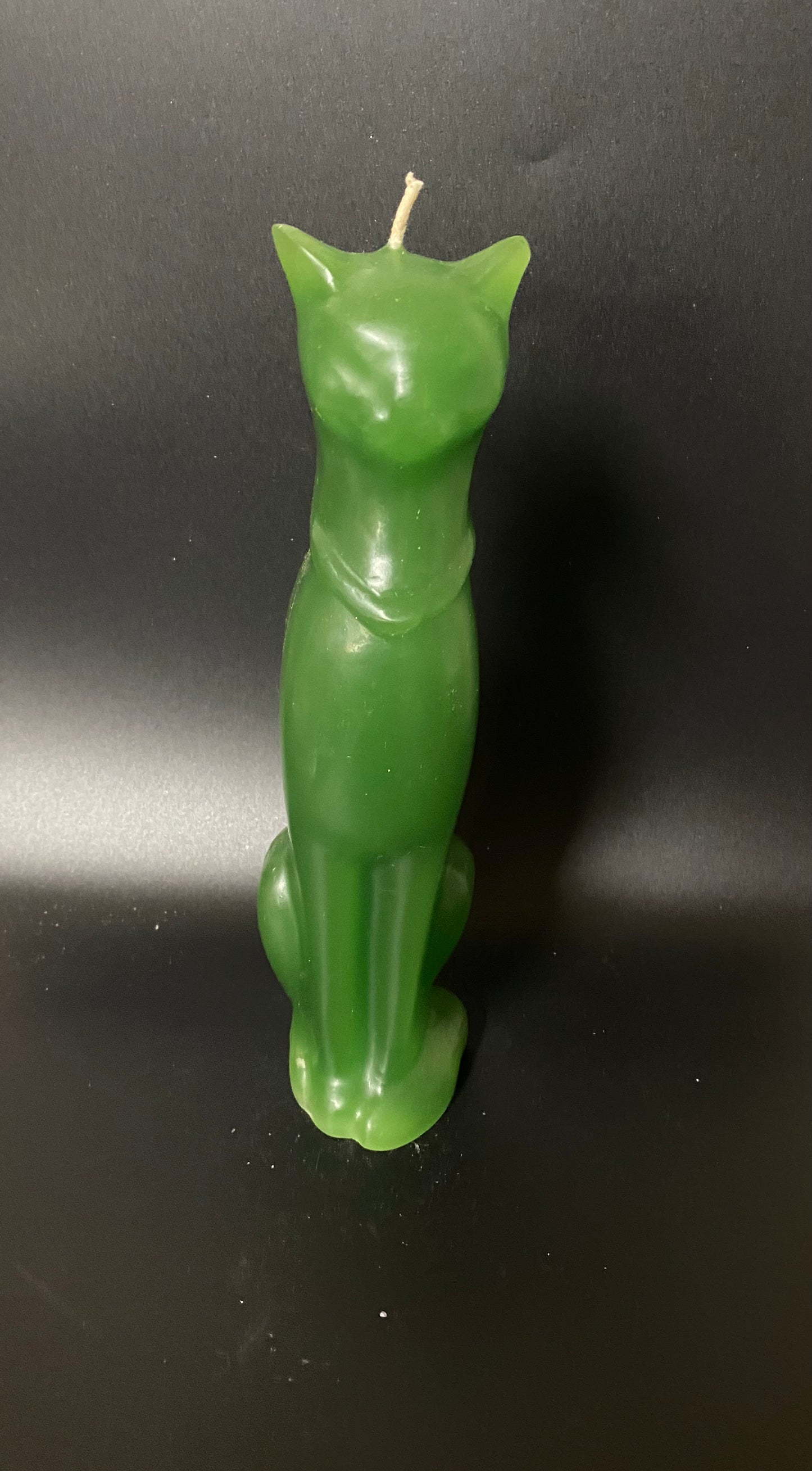 Green cat-shaped candle on a black background