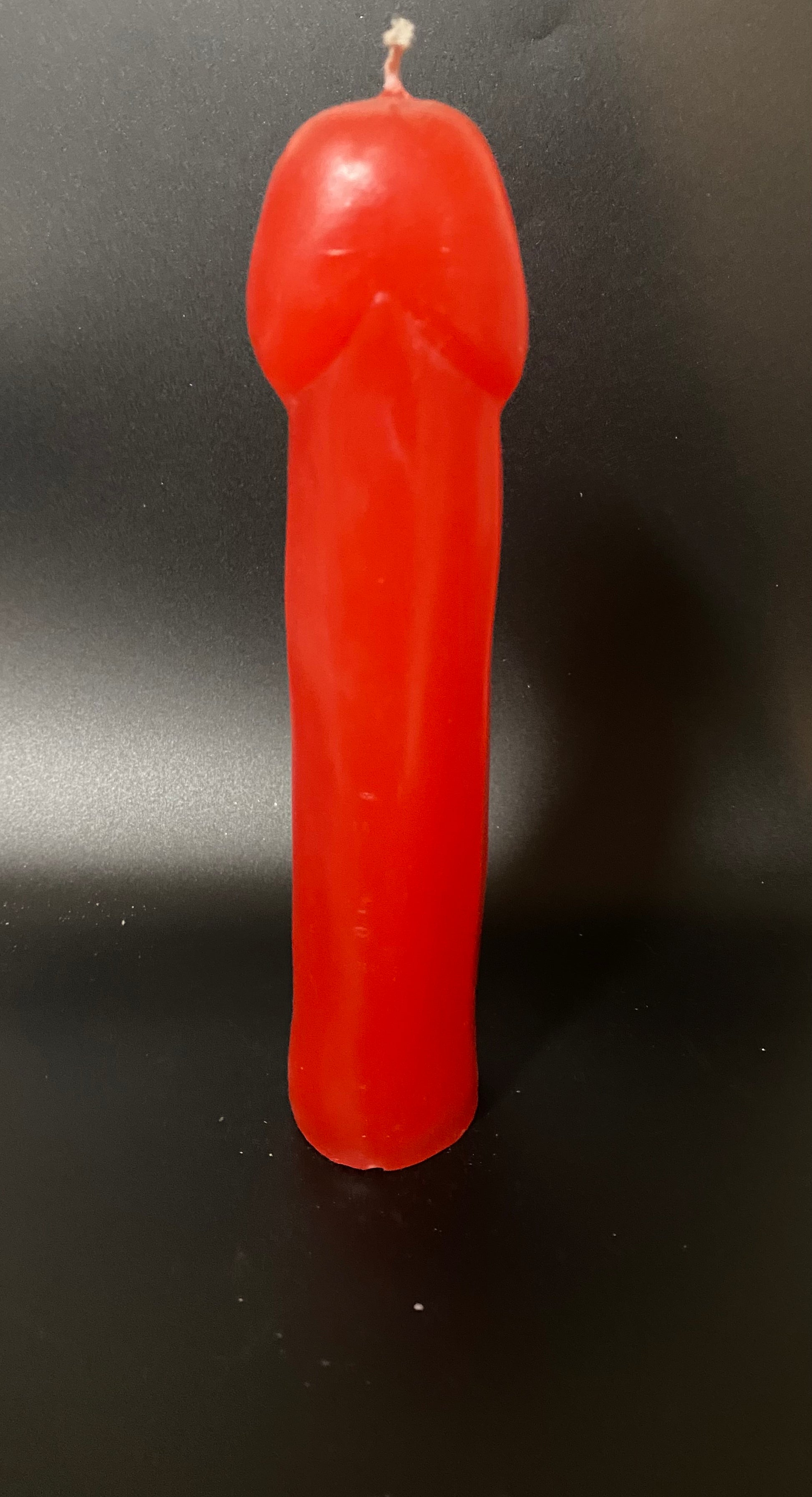 Red candle shaped like a gun on a black background