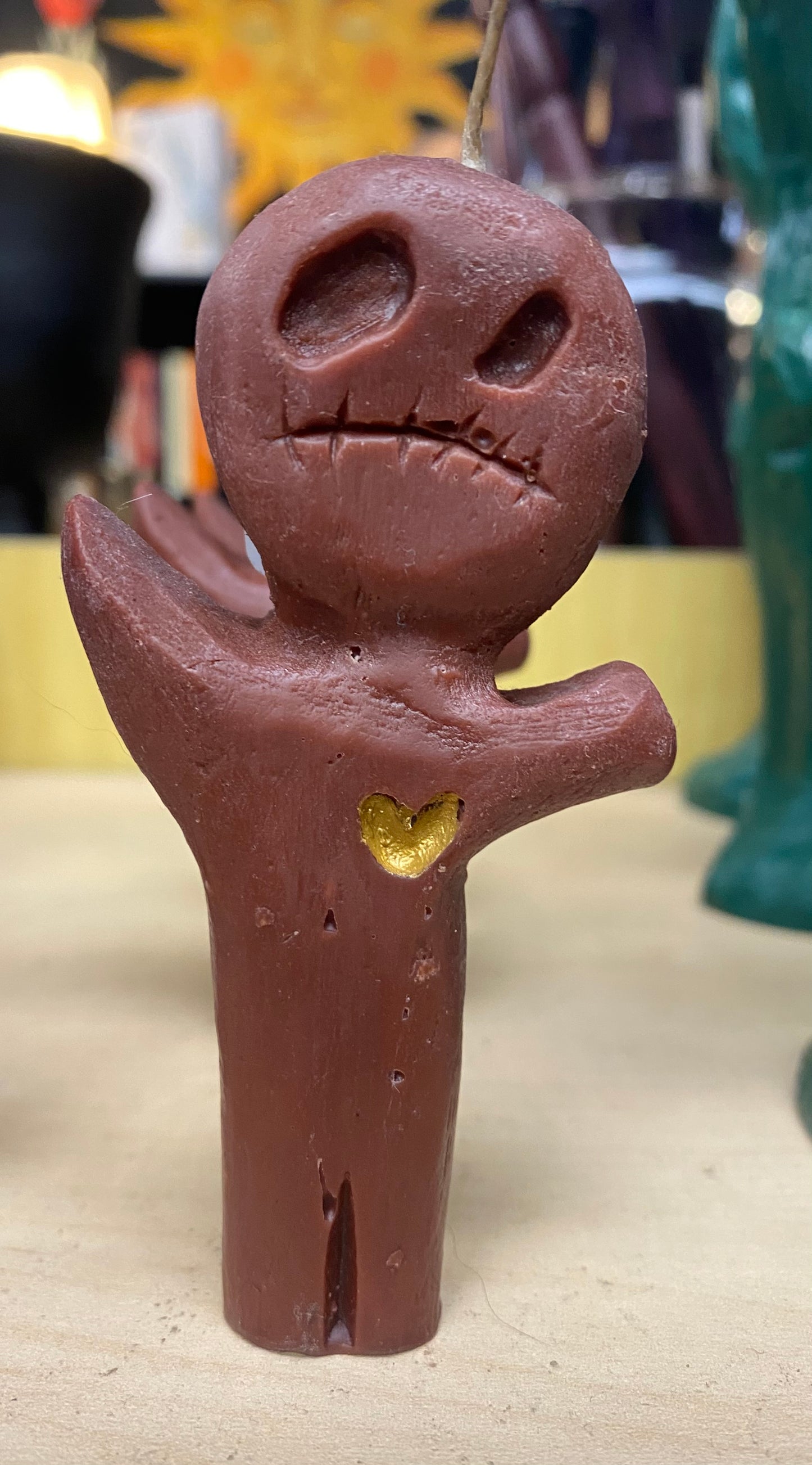 Candle figure with a face and heart detail on a neutral background