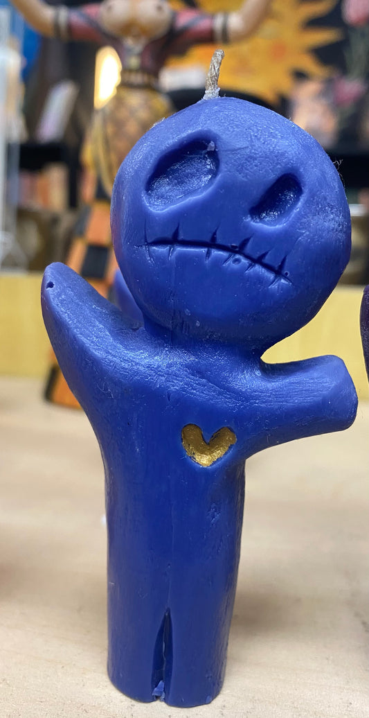 Blue candle shaped like a stylized character with a heart on its chest, against a blurred background.