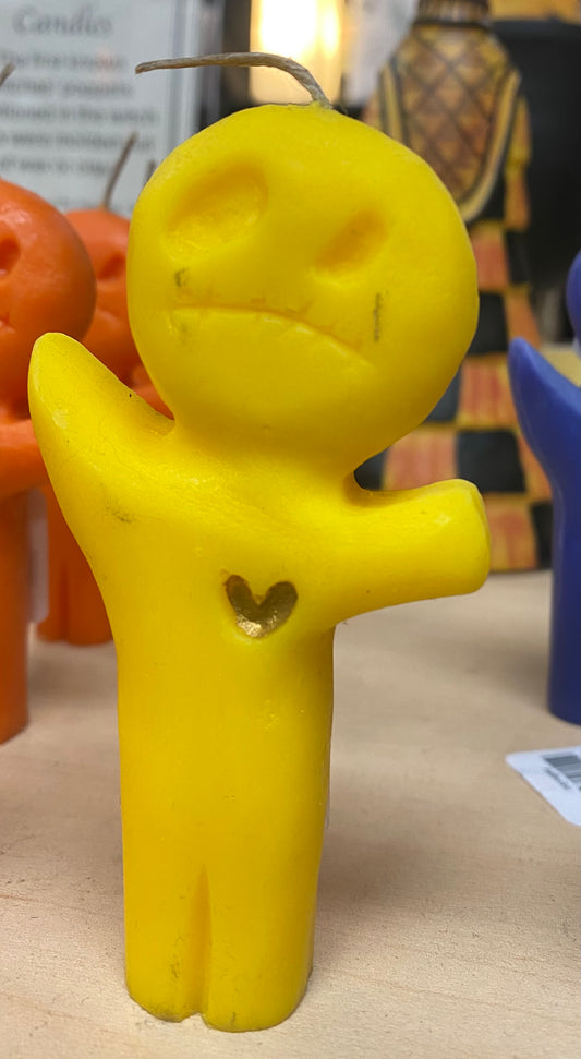 Yellow candle shaped like a stick figure with a heart on a table