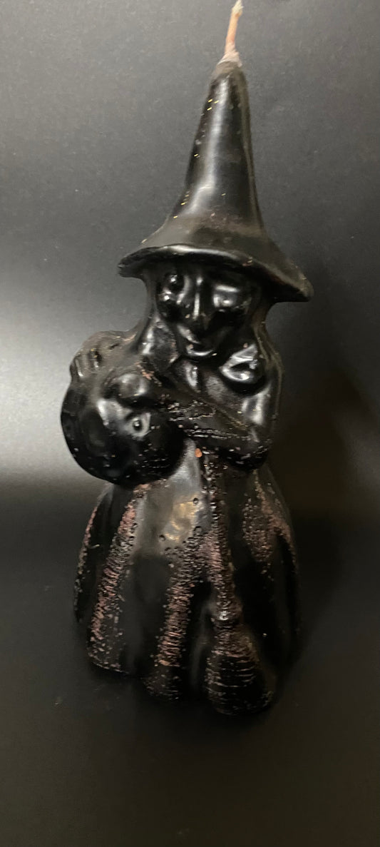 Black witch candle with pointed hat on a dark background