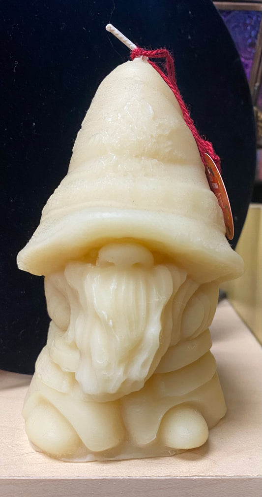 Candle shaped like a gnome with a pointed hat on a dark background