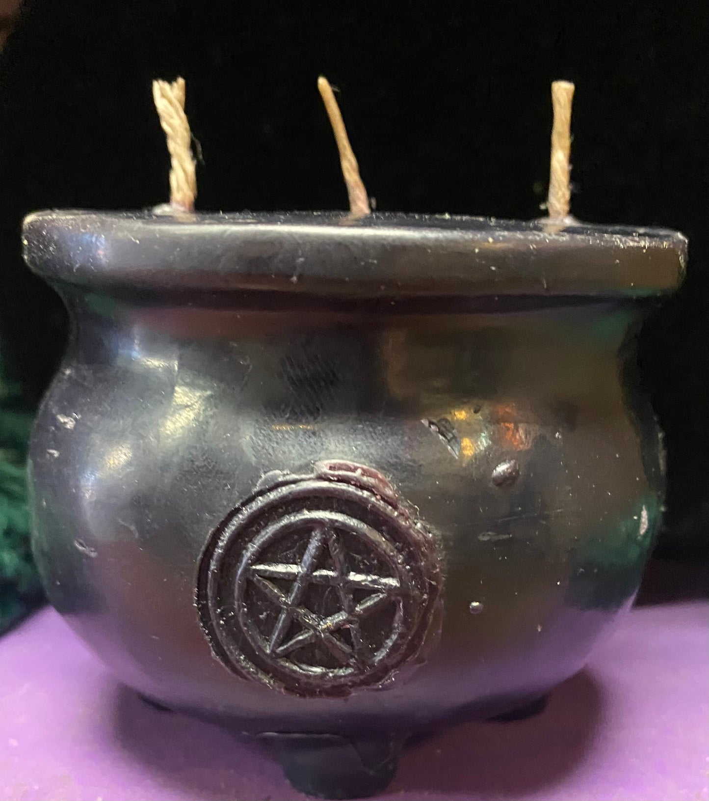 Black candle cauldron with a pentagram symbol on a dark background