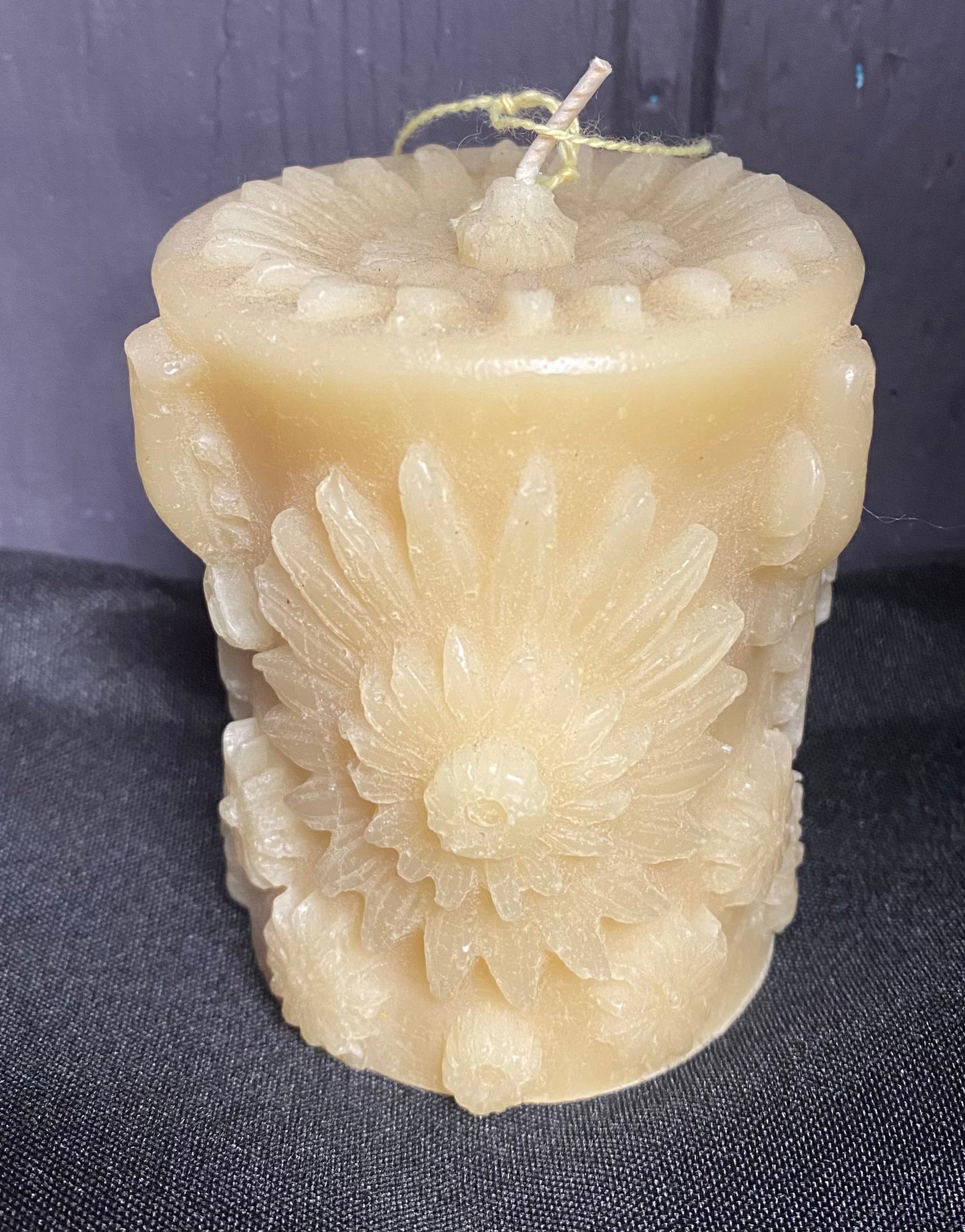 Decorative candle with floral patterns on a dark fabric background