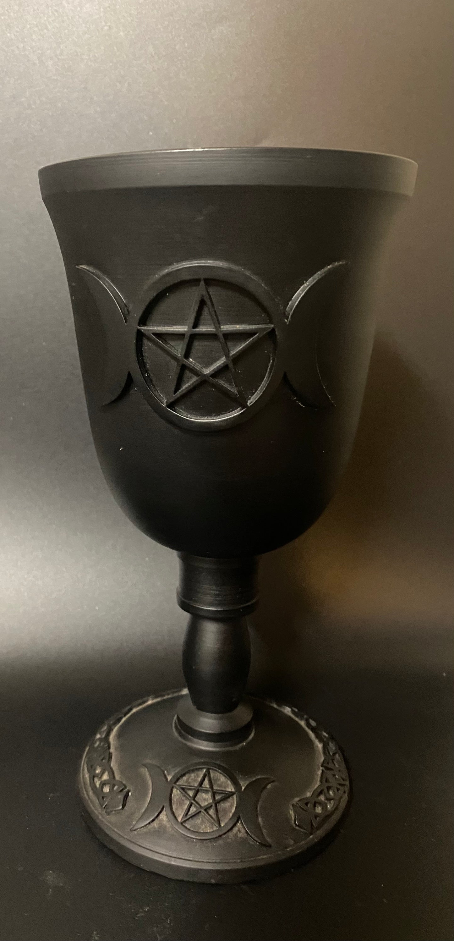 Black goblet with pentagram design on a gray background