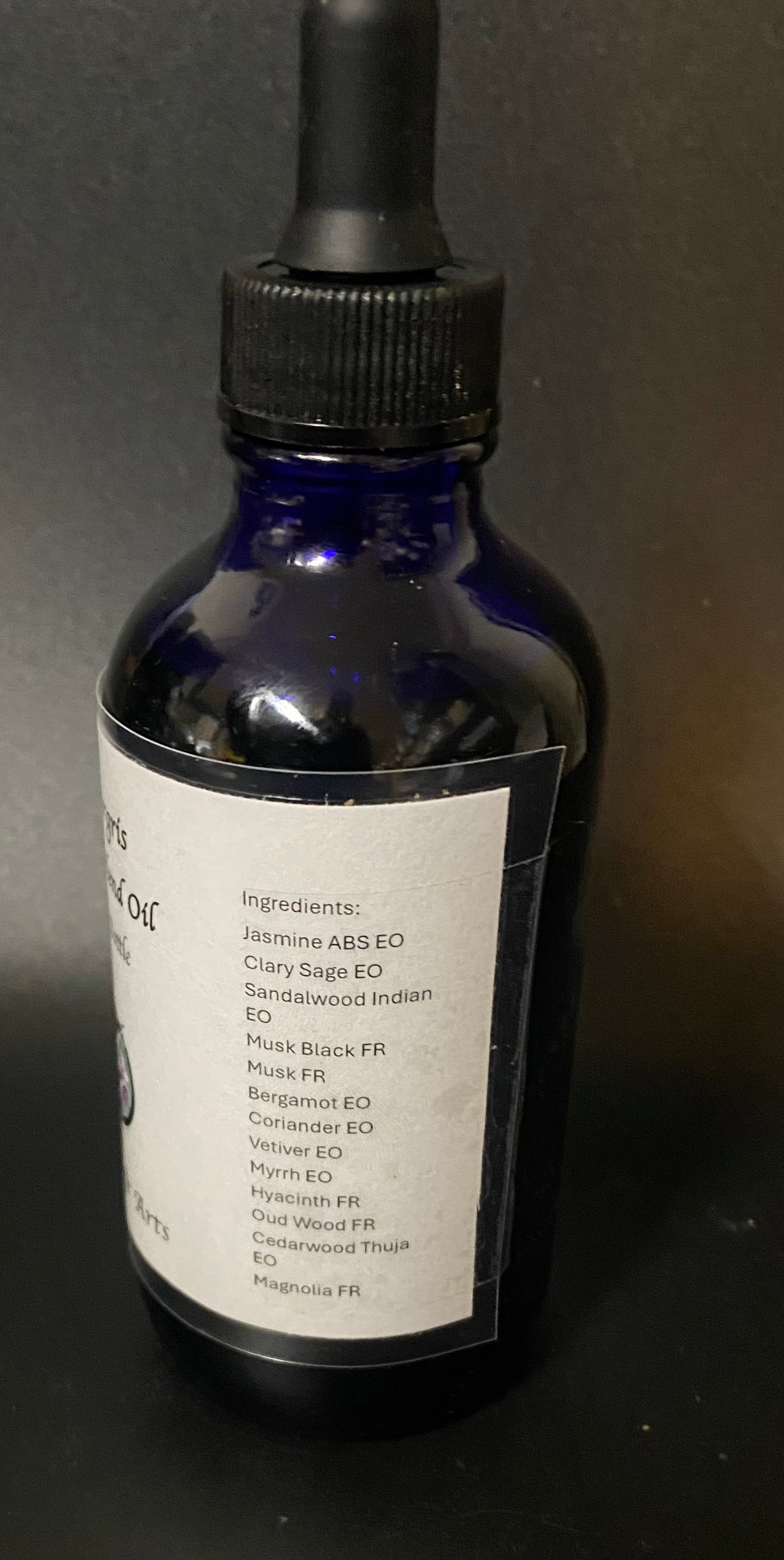 Blue glass bottle with dropper labeled 'Jasmine & Clary Sage' on a dark background