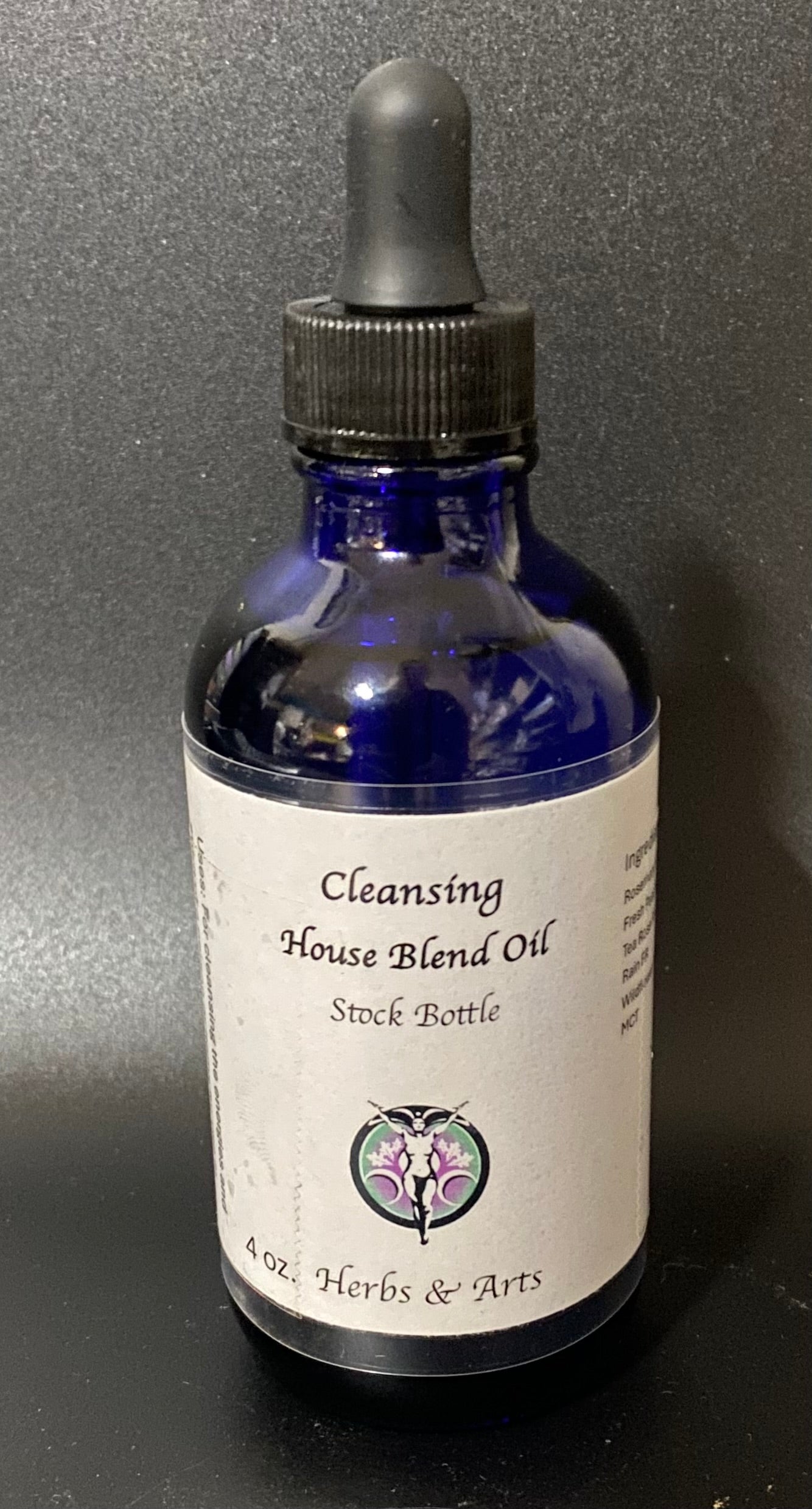 Bottle of Cleansing House Blend Oil with a dropper on a dark background