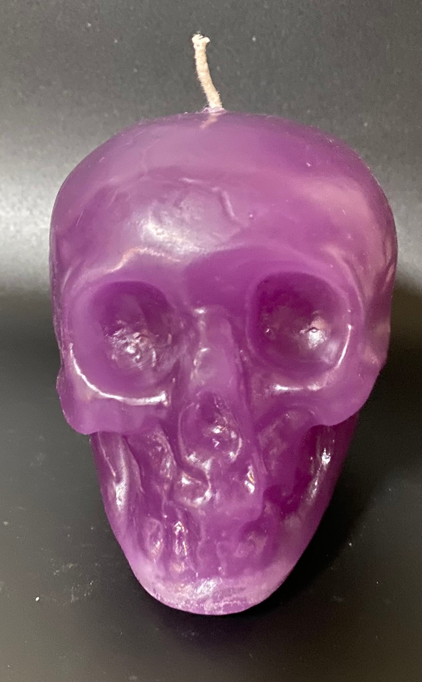 Purple skull-shaped candle on a dark background