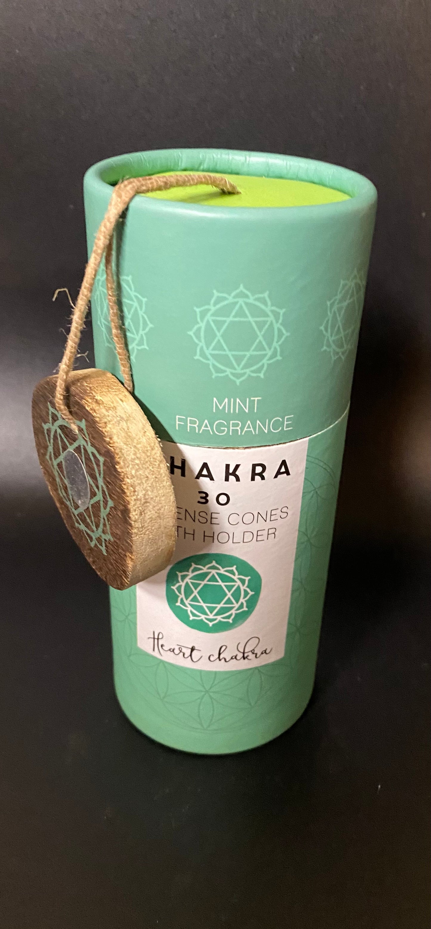 Mint-colored product with a label and wooden piece on a dark background