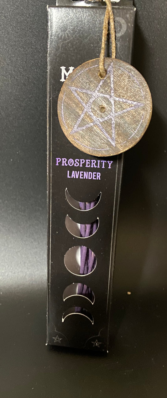 Decorative pentacle charm on a black box with moon phases, labeled 'Prosperity Lavender'.