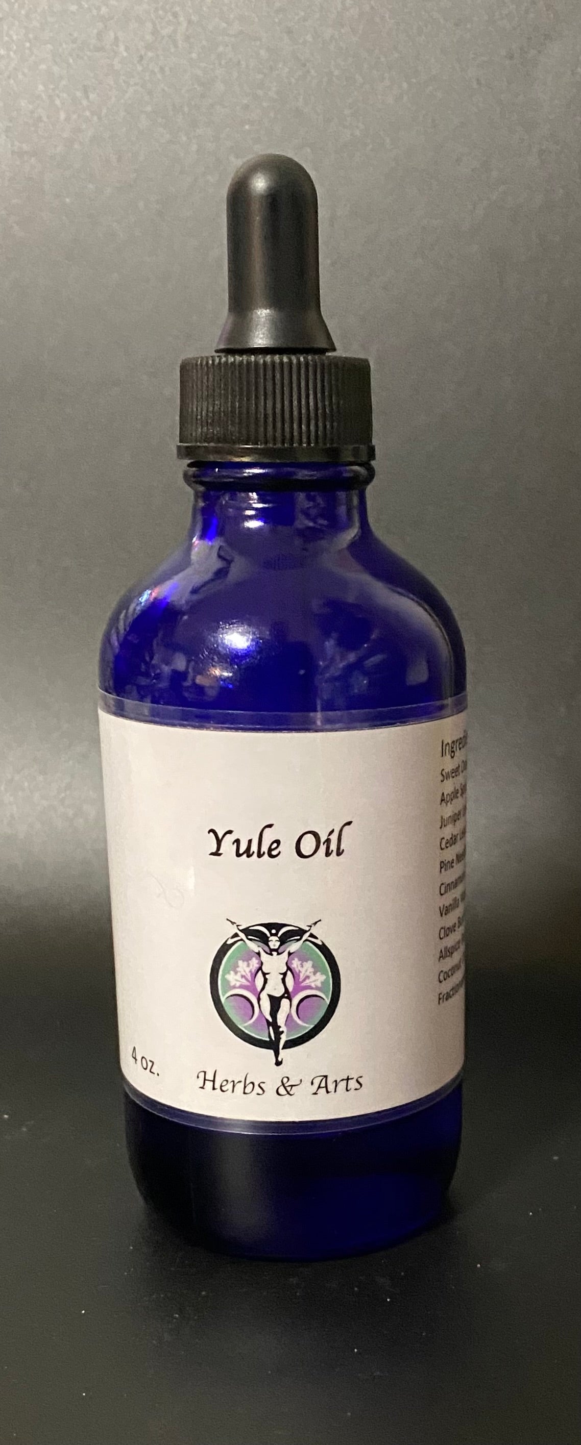 Blue bottle of Yule Oil with a dropper on a gray background