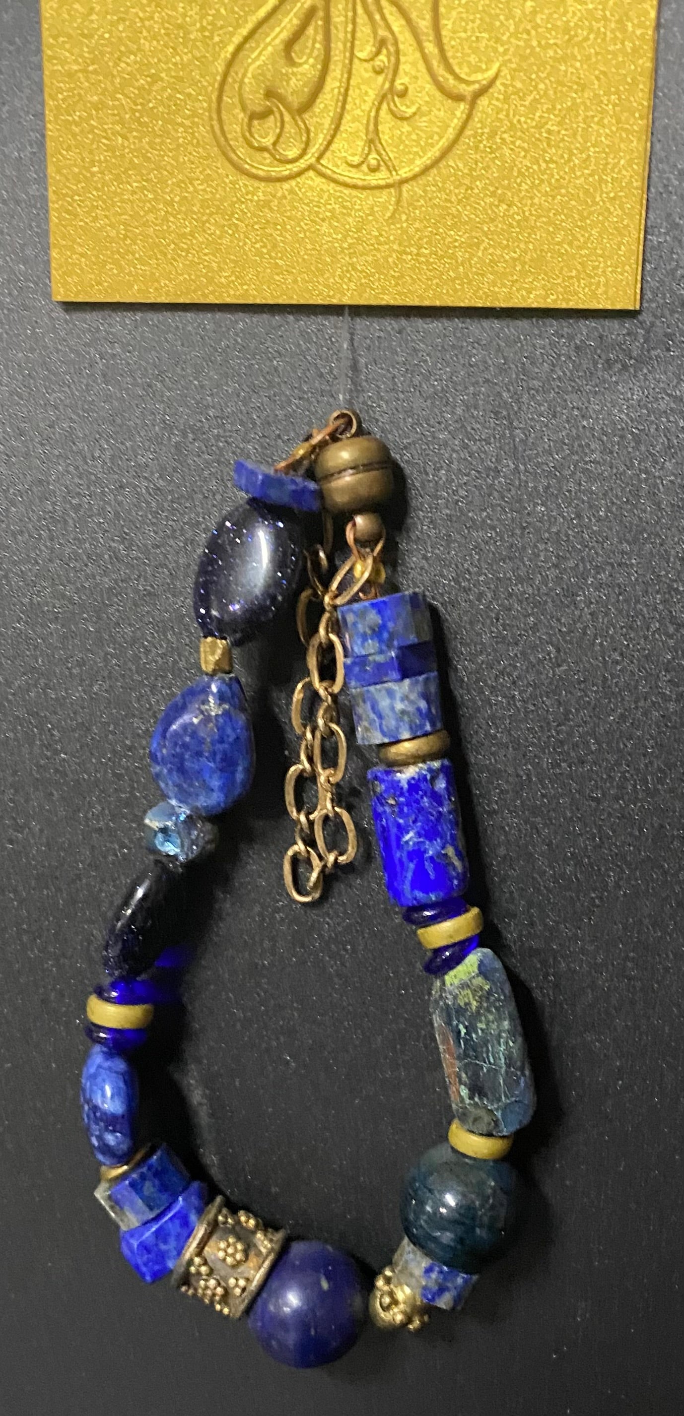 Blue beaded bracelet with gold accents on a dark surface