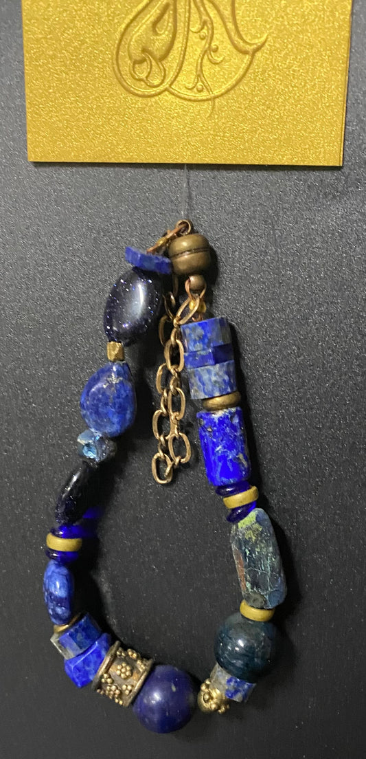 Blue beaded bracelet with gold accents on a dark surface