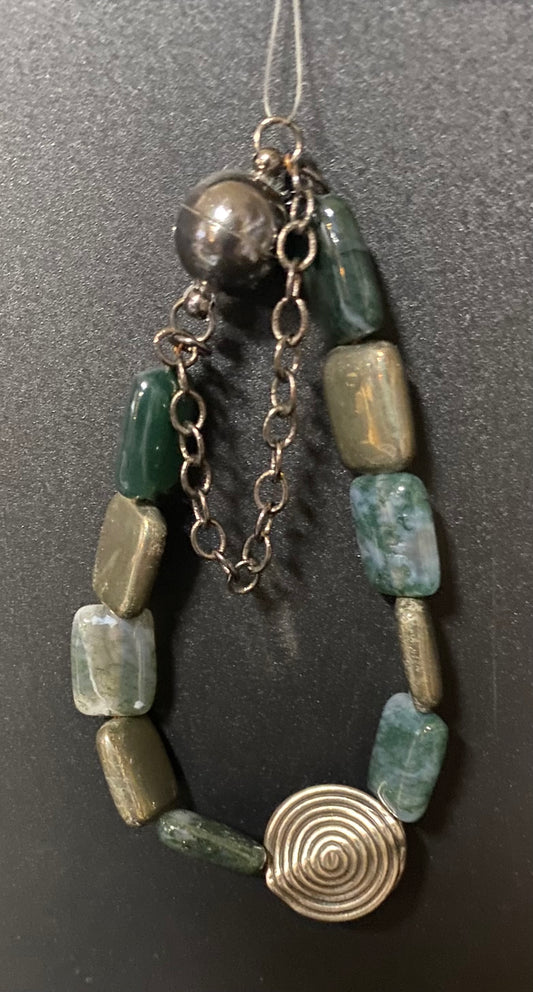 Jewelry with green beads and a metal spiral on a dark background