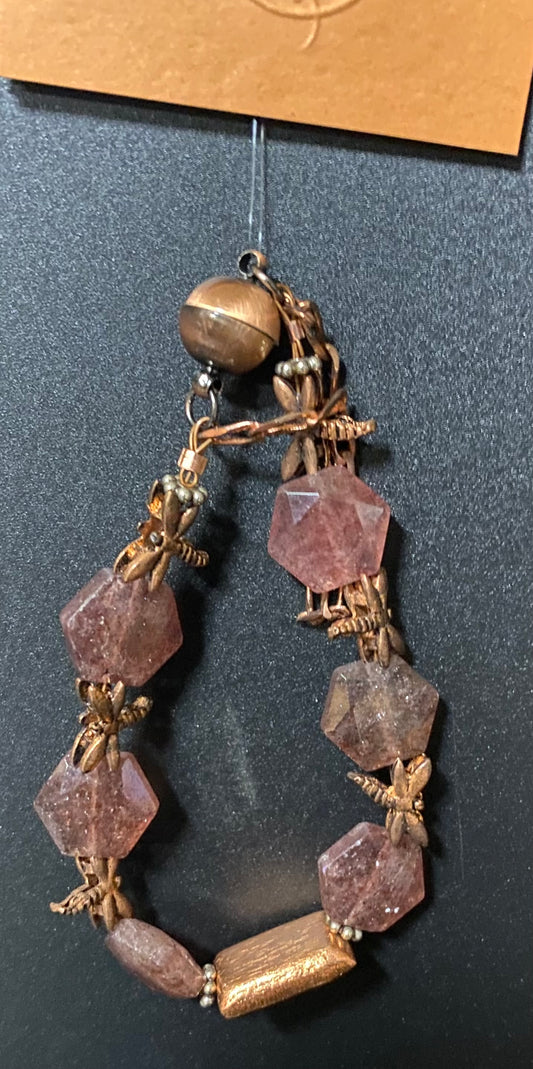 Decorative necklace with purple beads and gold accents on a dark surface