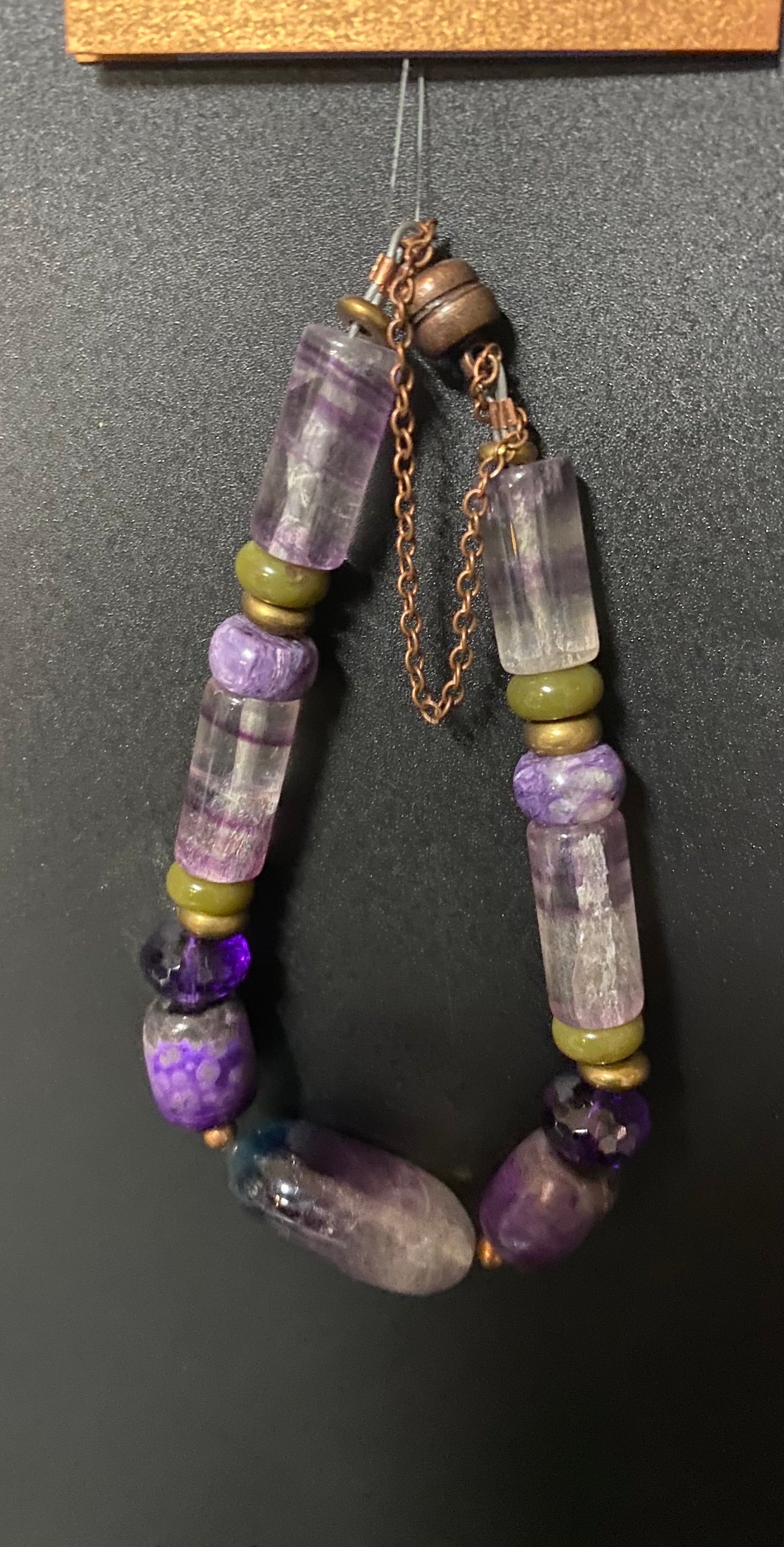Necklace with purple and green beads on a dark background