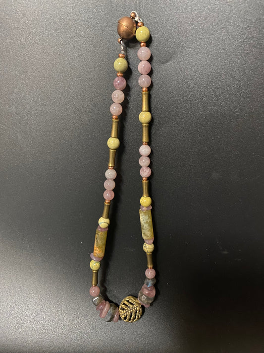 Beaded necklace with gold and bronze accents on a dark surface