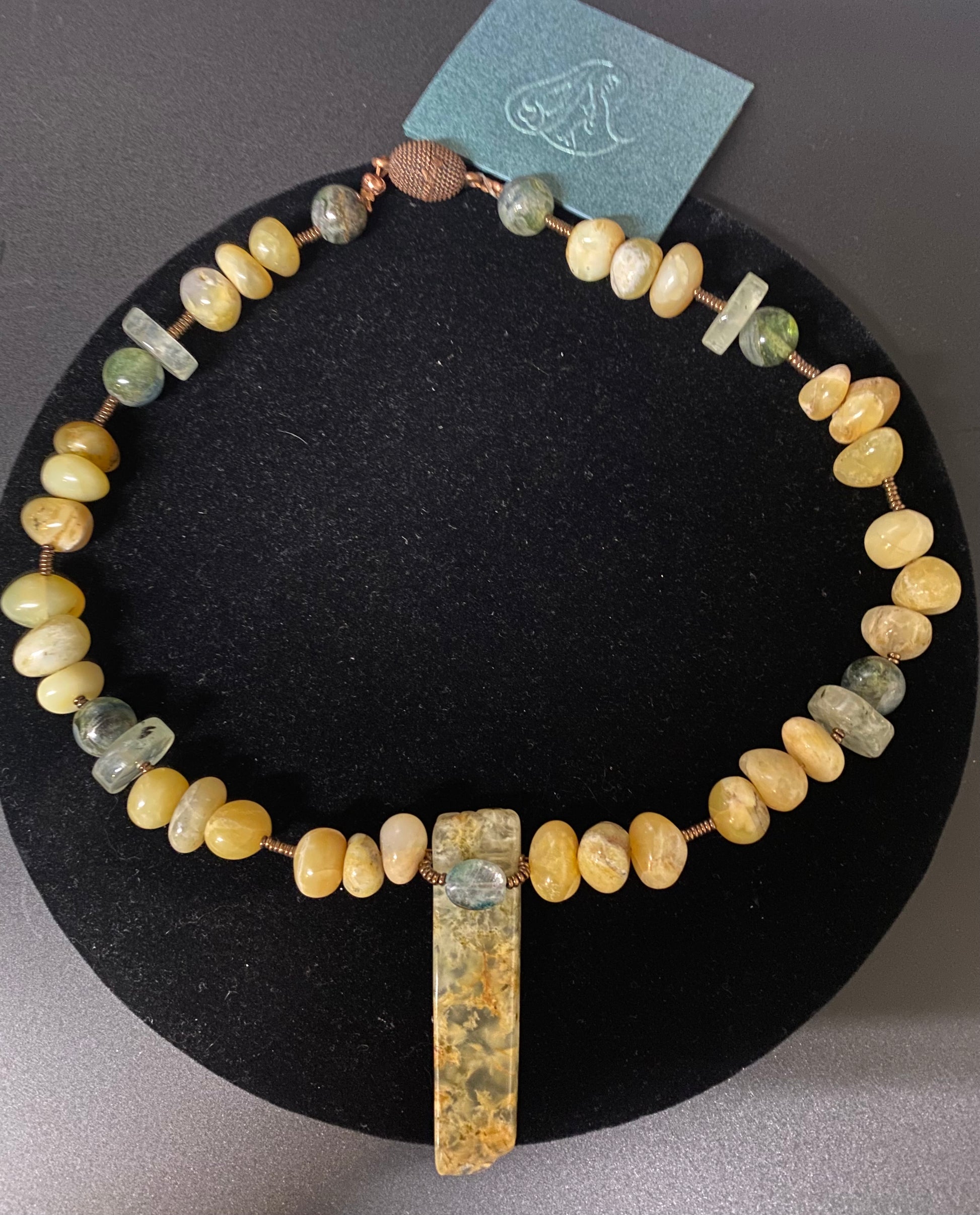 Necklace with beaded design and pendant on a black stand