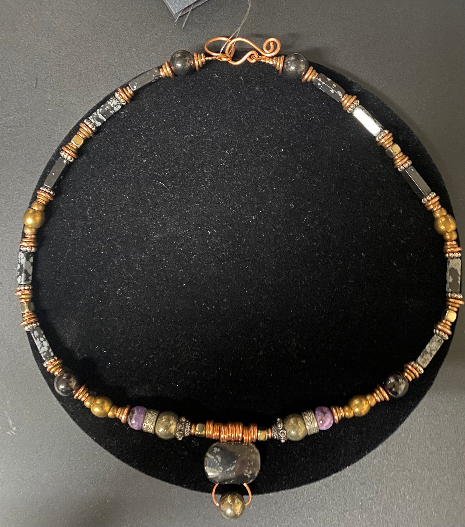 Beaded necklace with a pendant on a black stand