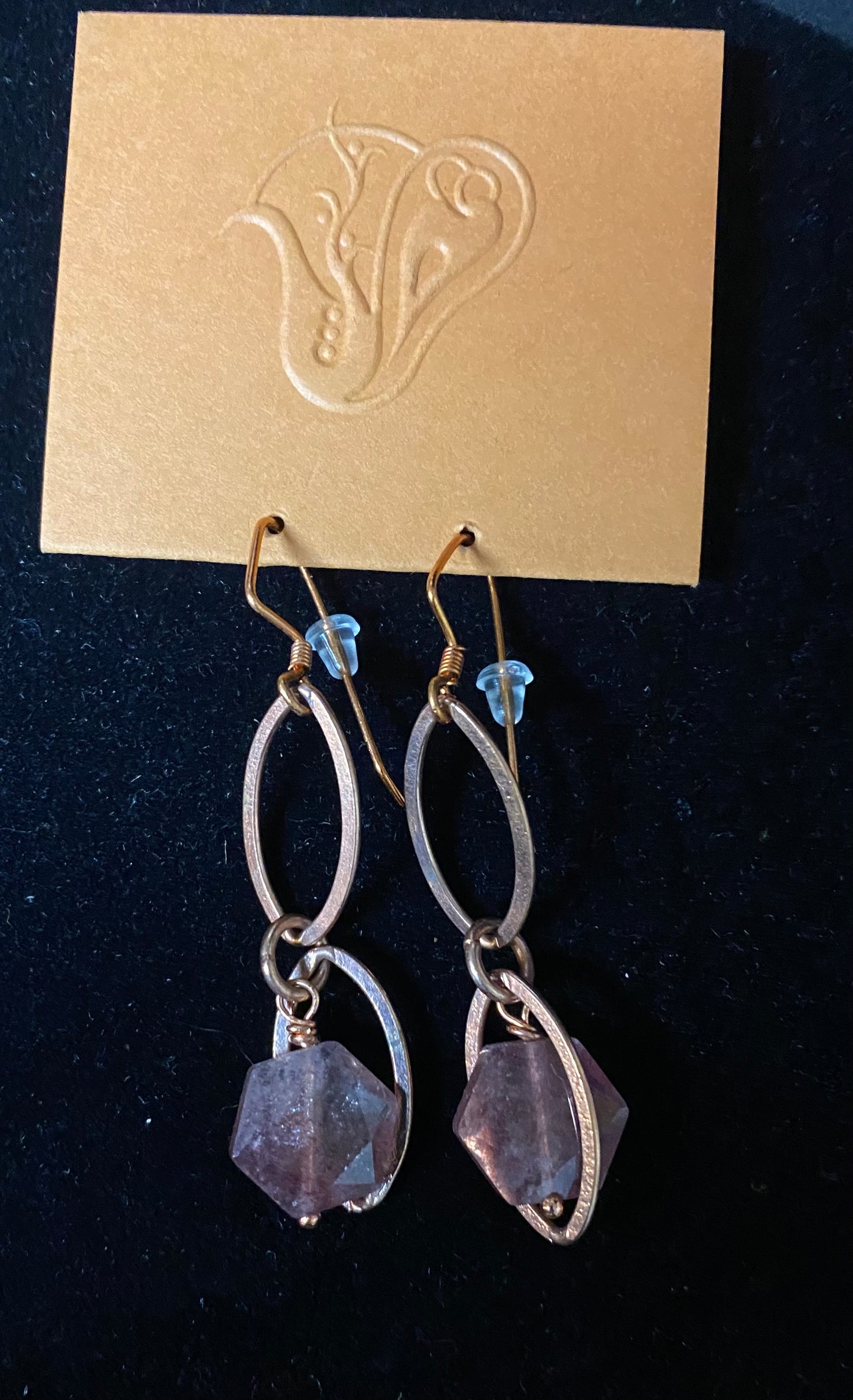 Pair of silver earrings with purple gemstones on a dark background