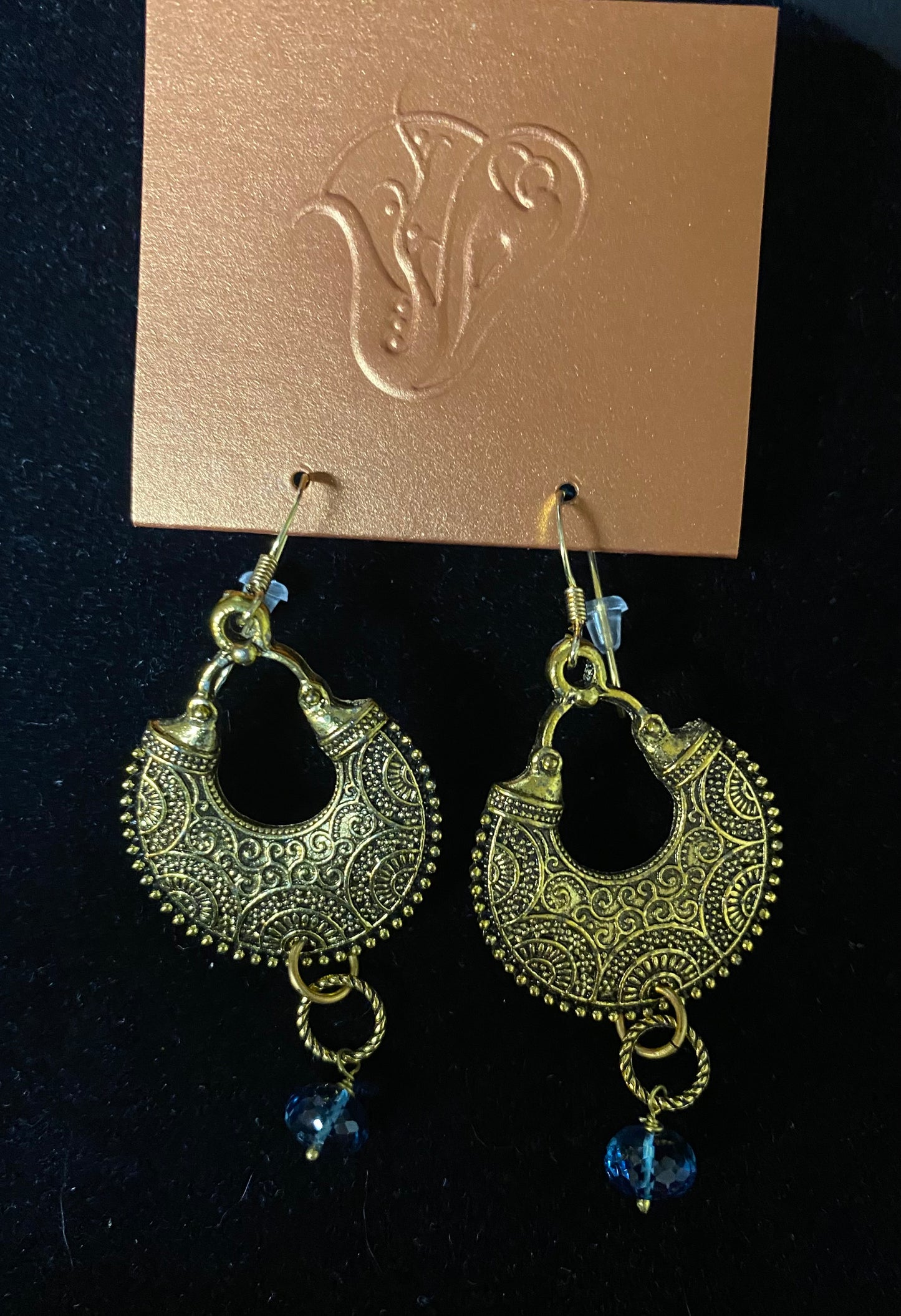Pair of gold earrings with blue beads on a black background
