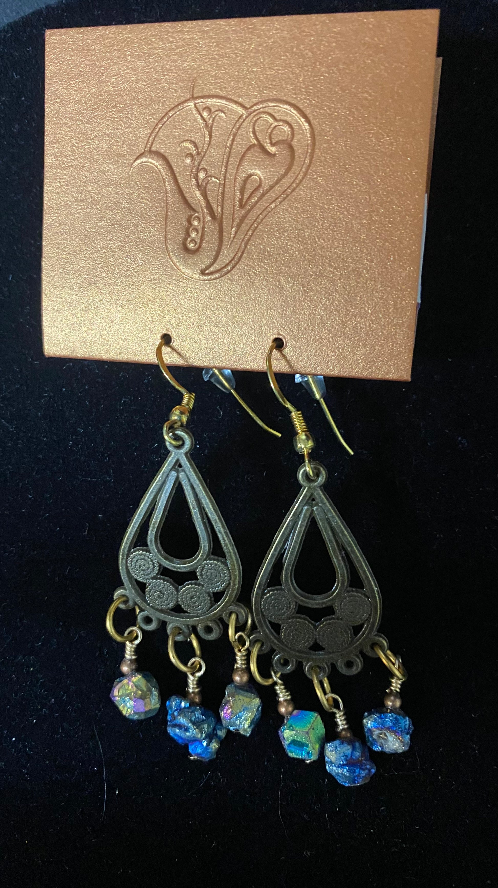 Pair of black teardrop earrings with blue beads on a gold card with a floral design.