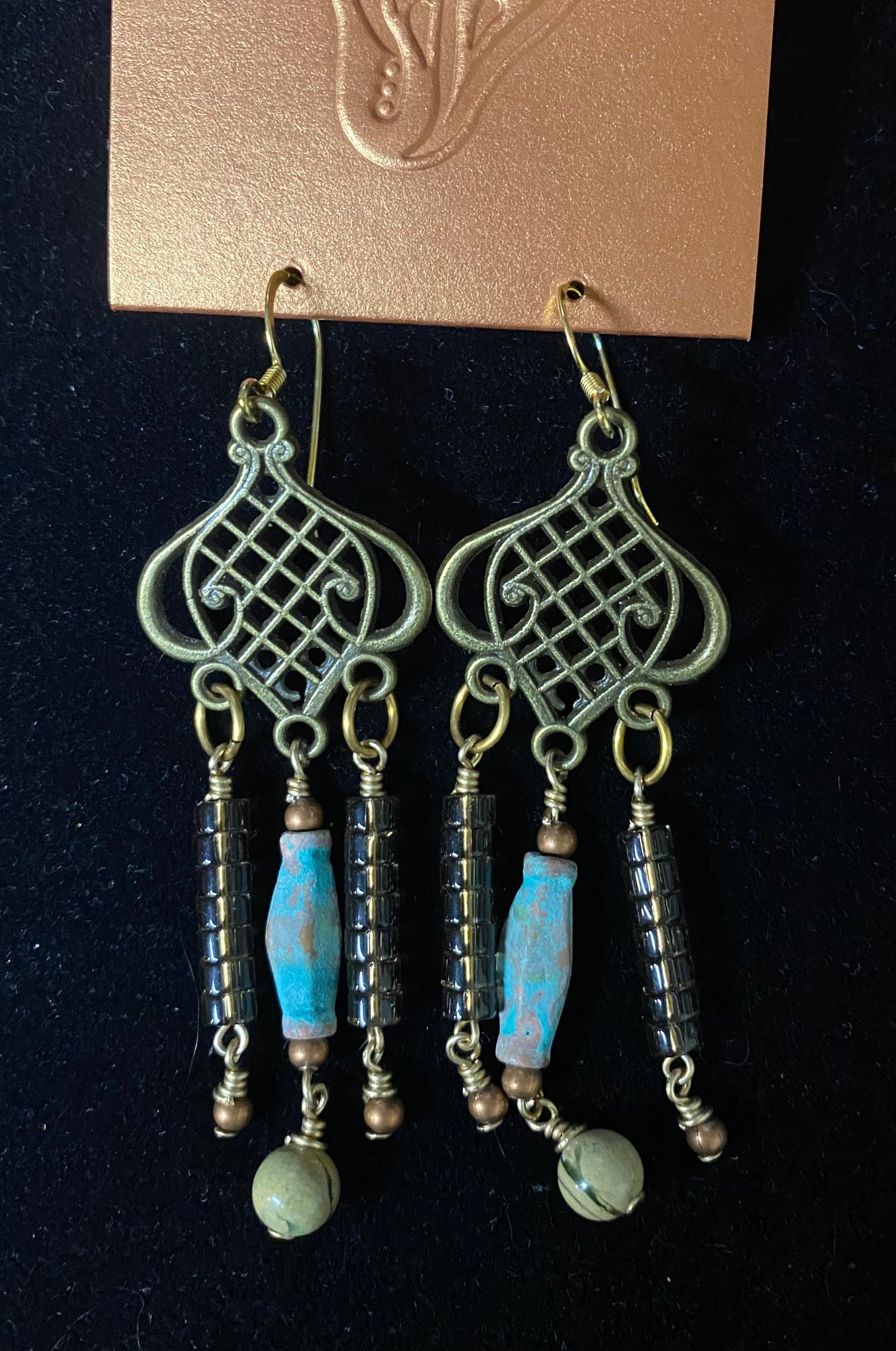 Pair of earrings with blue and green beads on a black background
