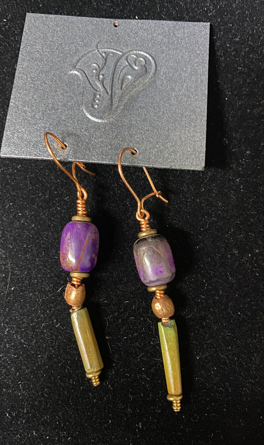 Pair of earrings with purple and green beads on a black background