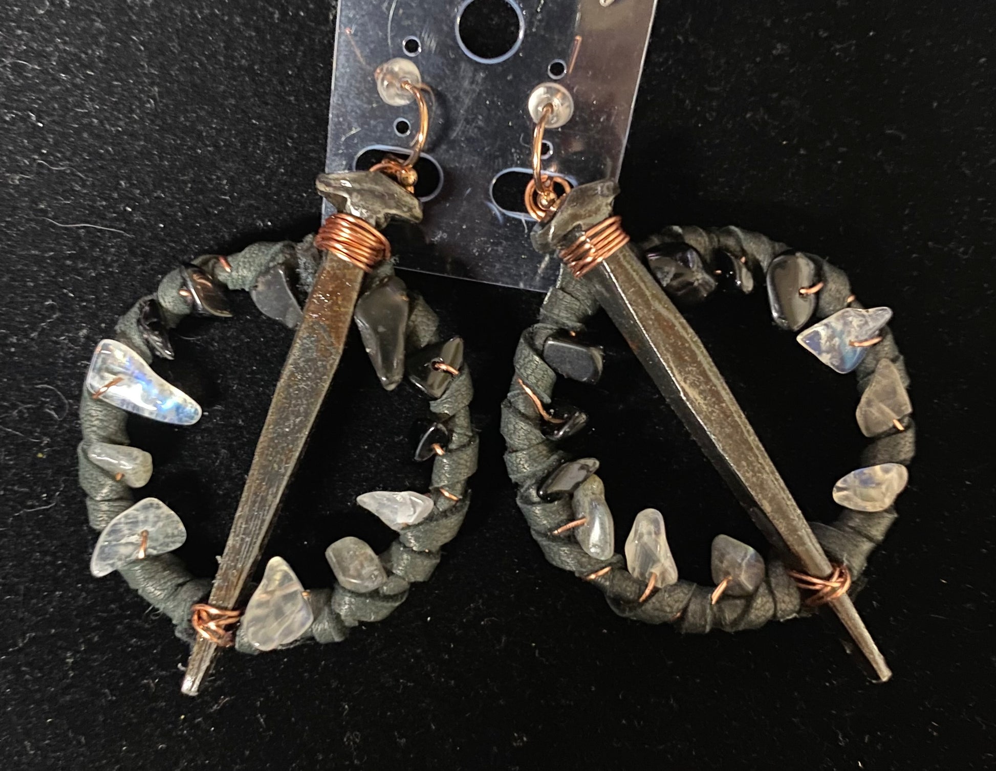 Pair of earrings with stone-like beads and metal components on a dark background