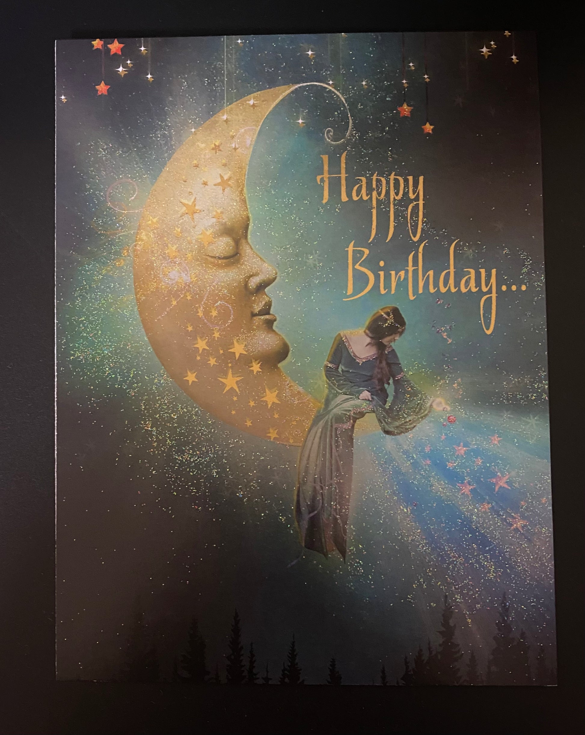 Greeting card with a celestial design featuring a face on a moon and a person, with 'Happy Birthday' text.