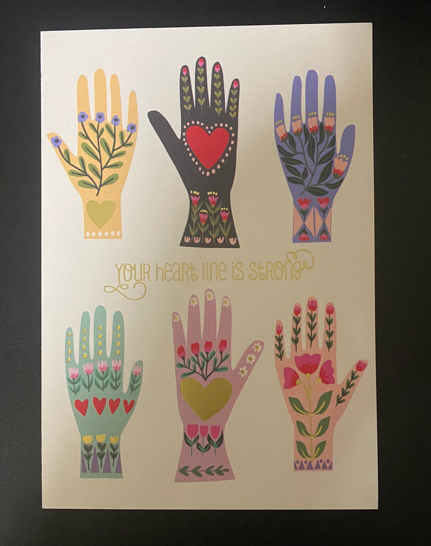 Card with colorful illustrations of hands with floral designs on a beige background.
