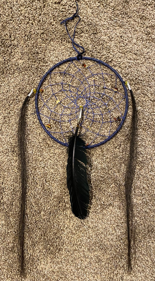 Dreamcatcher with feathers on a sandy surface